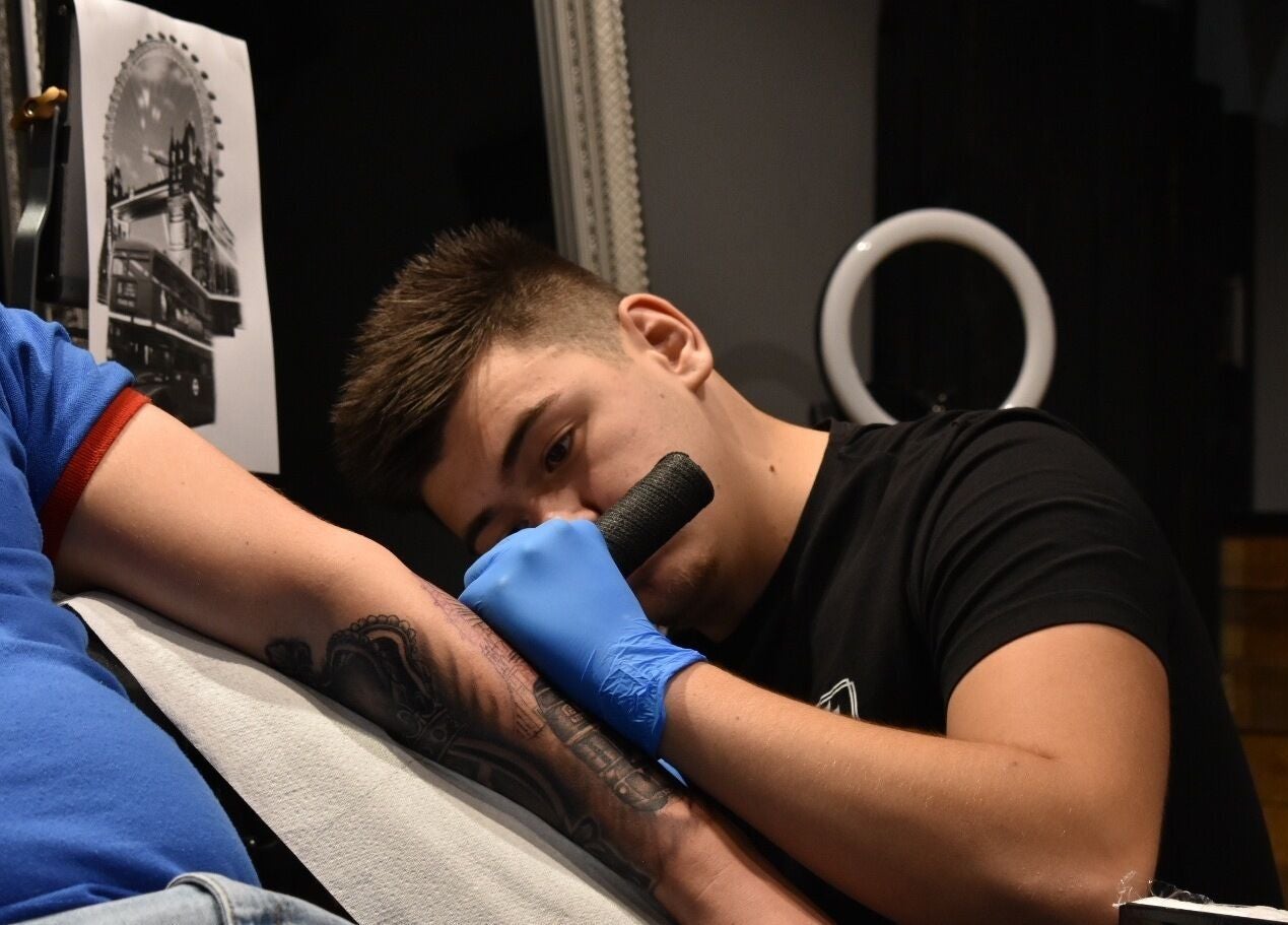 Tattoo artist at Salon Transilvania in Cluj-Napoca, Județul Cluj, RO applying a detailed arm tattoo.