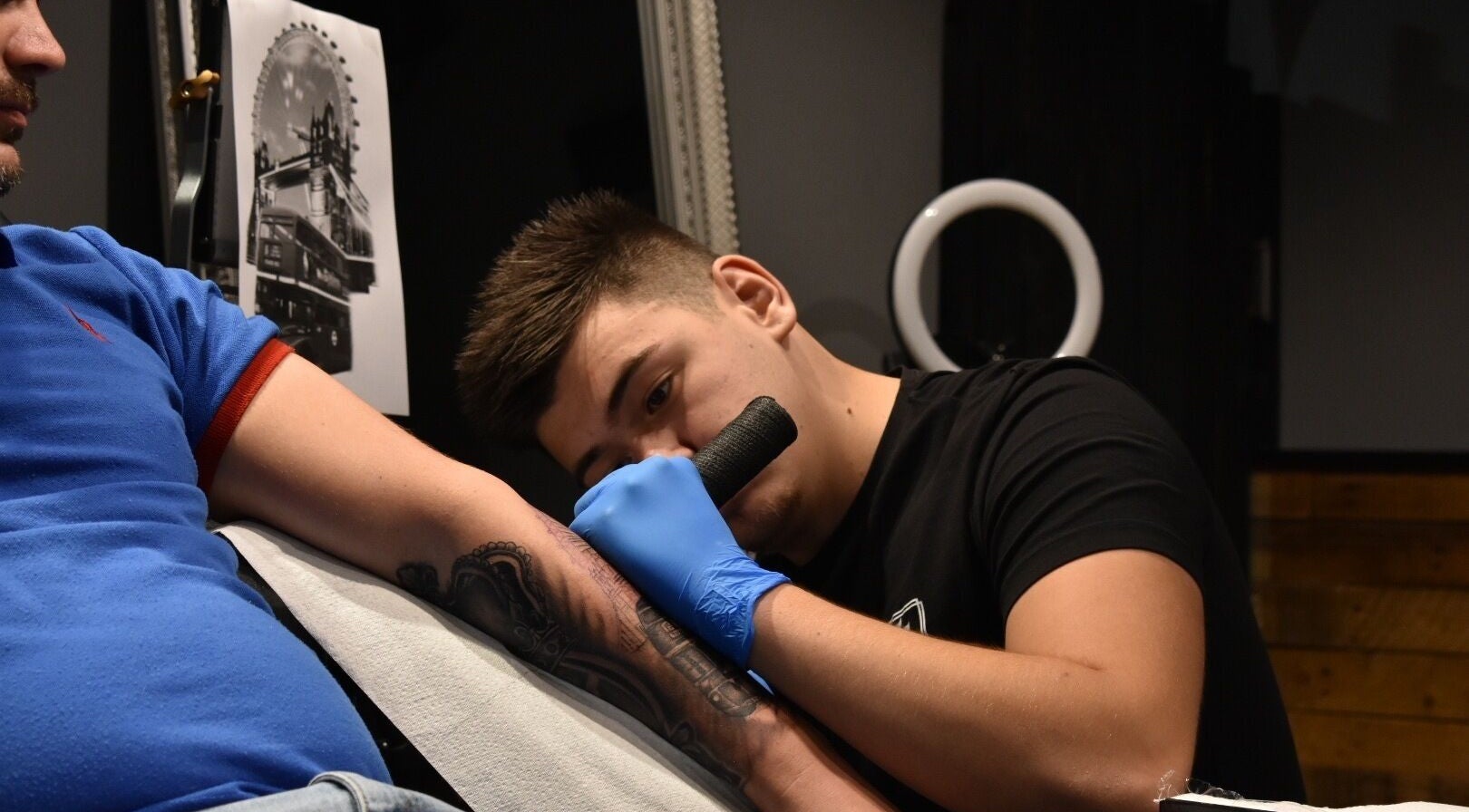 Tattoo artist at Salon Transilvania in Cluj-Napoca, Județul Cluj, RO applying a detailed arm tattoo.