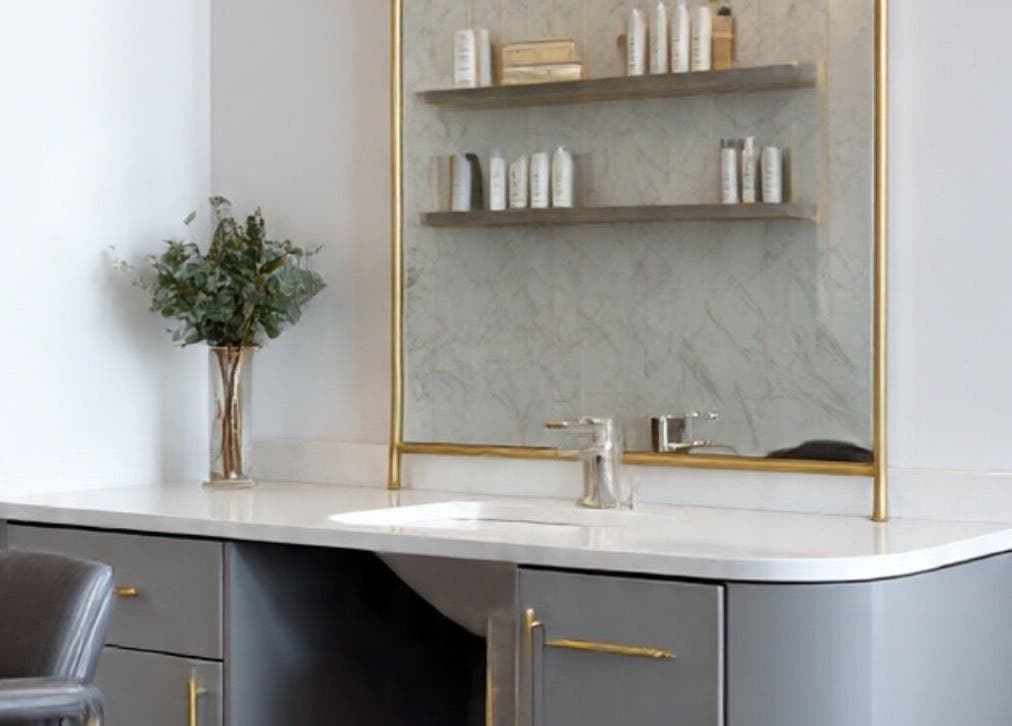 Luxurious salon vanity at LuxehairbyJo, Wellington, Florida, US with gold accents and beauty products.