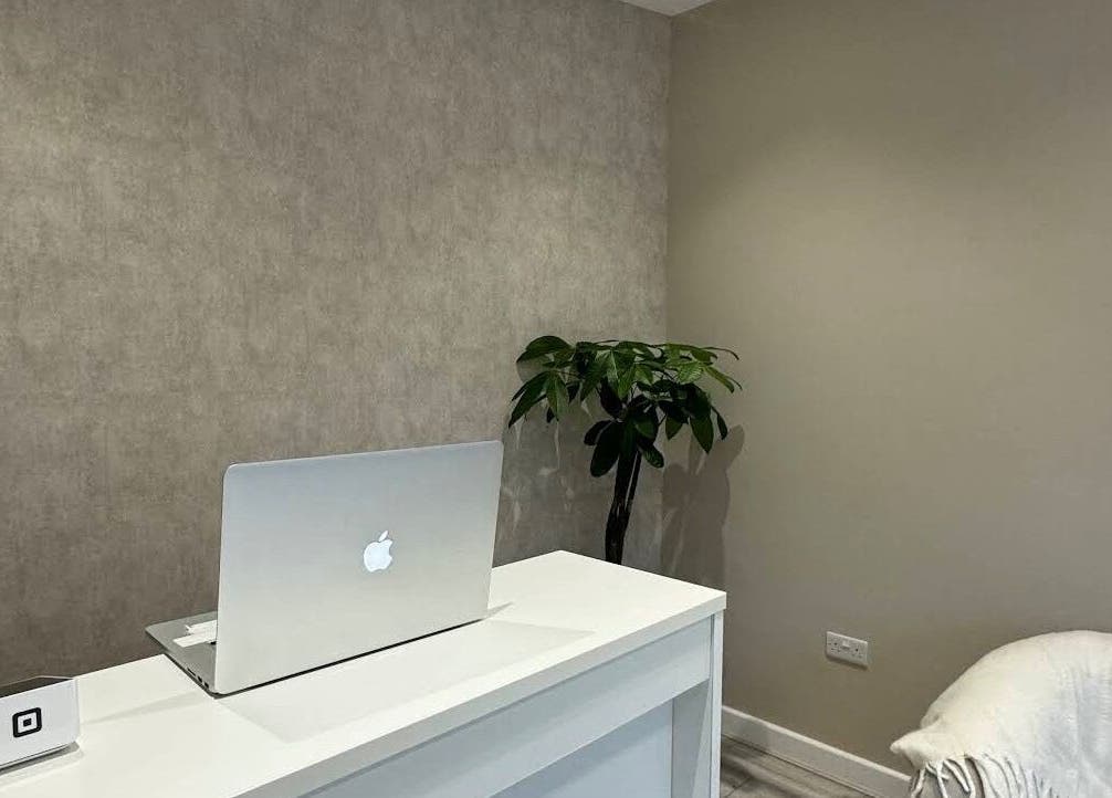 Elegant reception desk at Eskeen Clinic, London, England, GB. Modern design with a laptop and plant.
