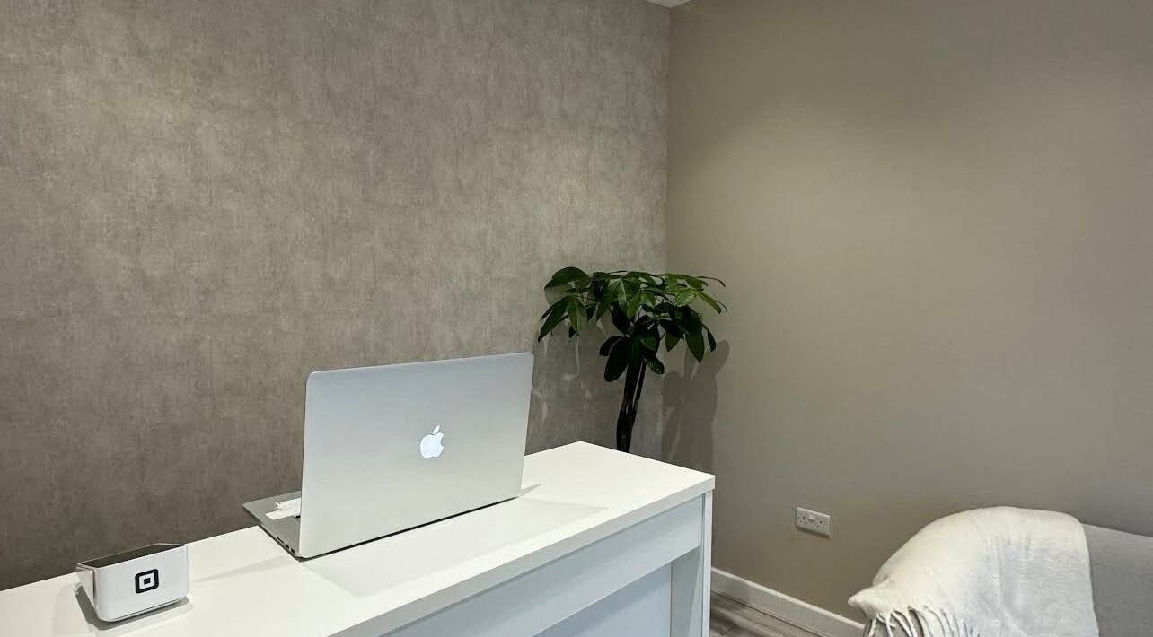 Elegant reception desk at Eskeen Clinic, London, England, GB. Modern design with a laptop and plant.