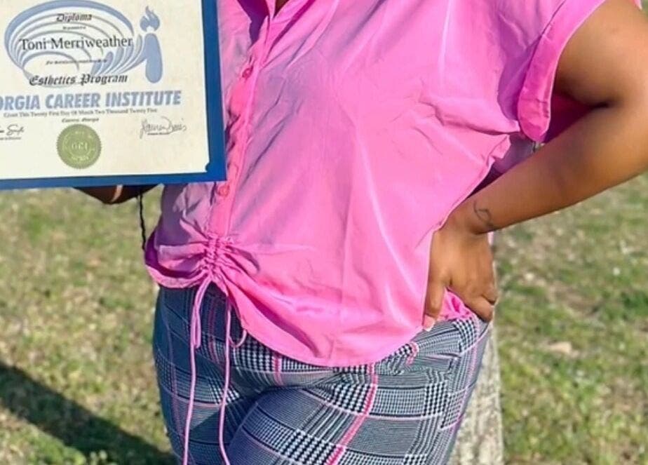 Proud graduate holding esthetics diploma at iLondon Esthetics, Muskegon, Michigan, US.