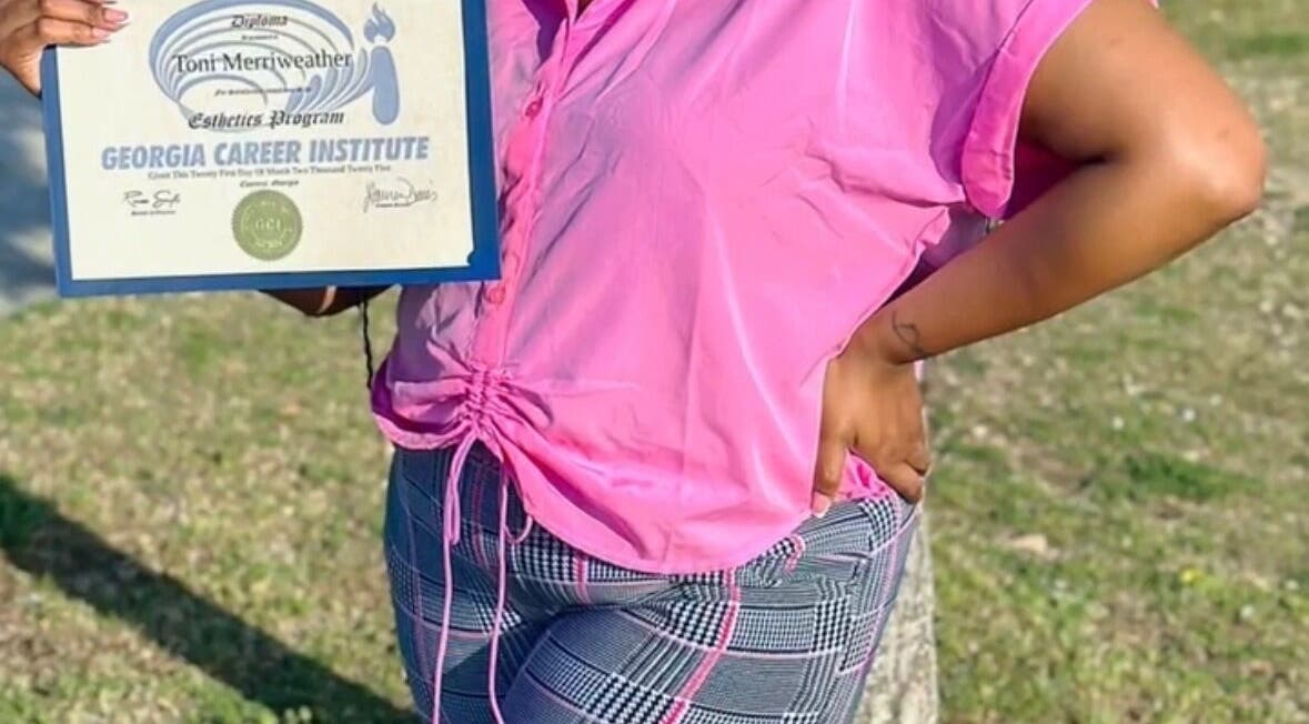 Proud graduate holding esthetics diploma at iLondon Esthetics, Muskegon, Michigan, US.