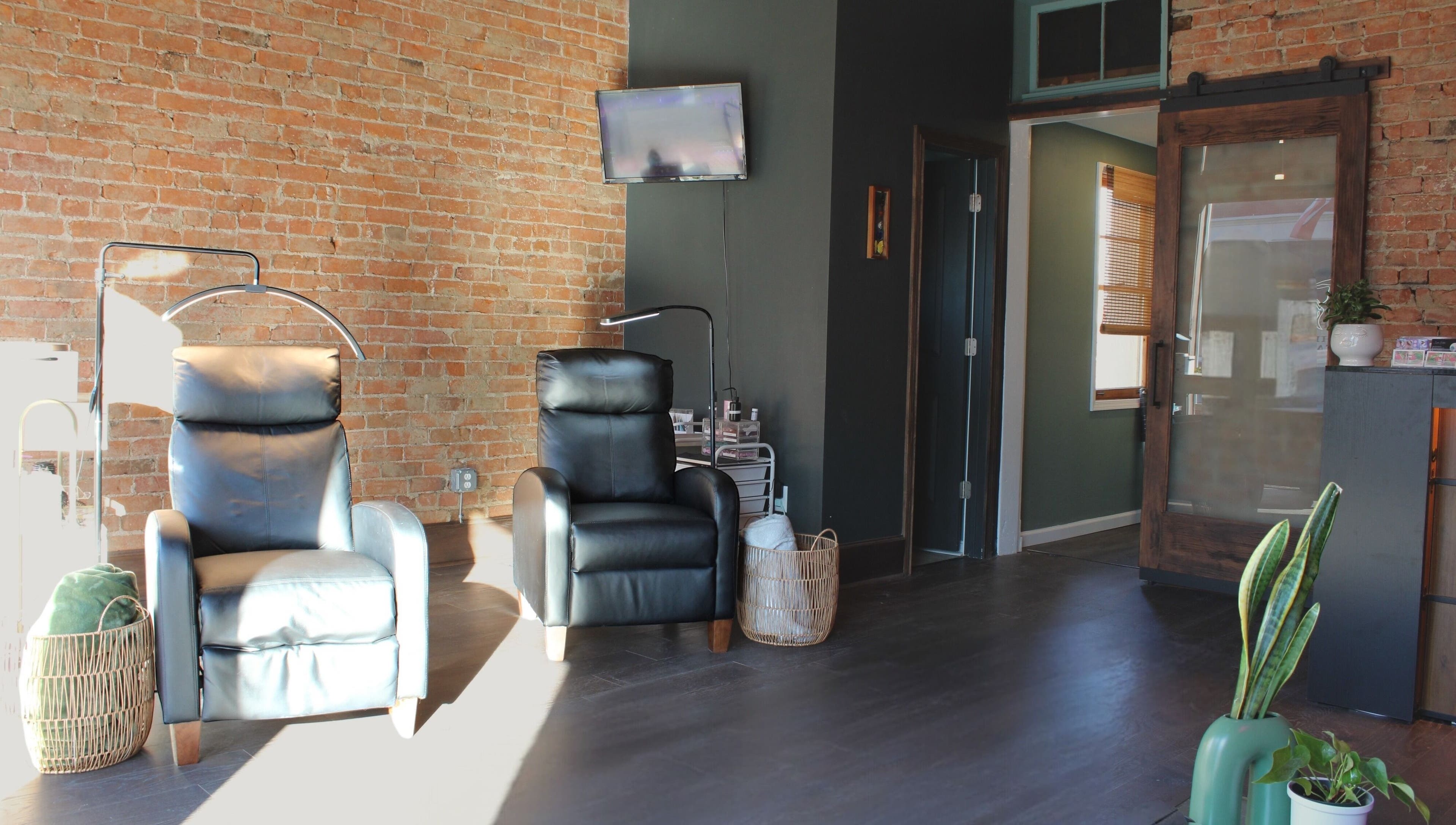 Modern and cozy seating at Orbit Esthetics, Covington, Kentucky, US with leather chairs and brick walls.