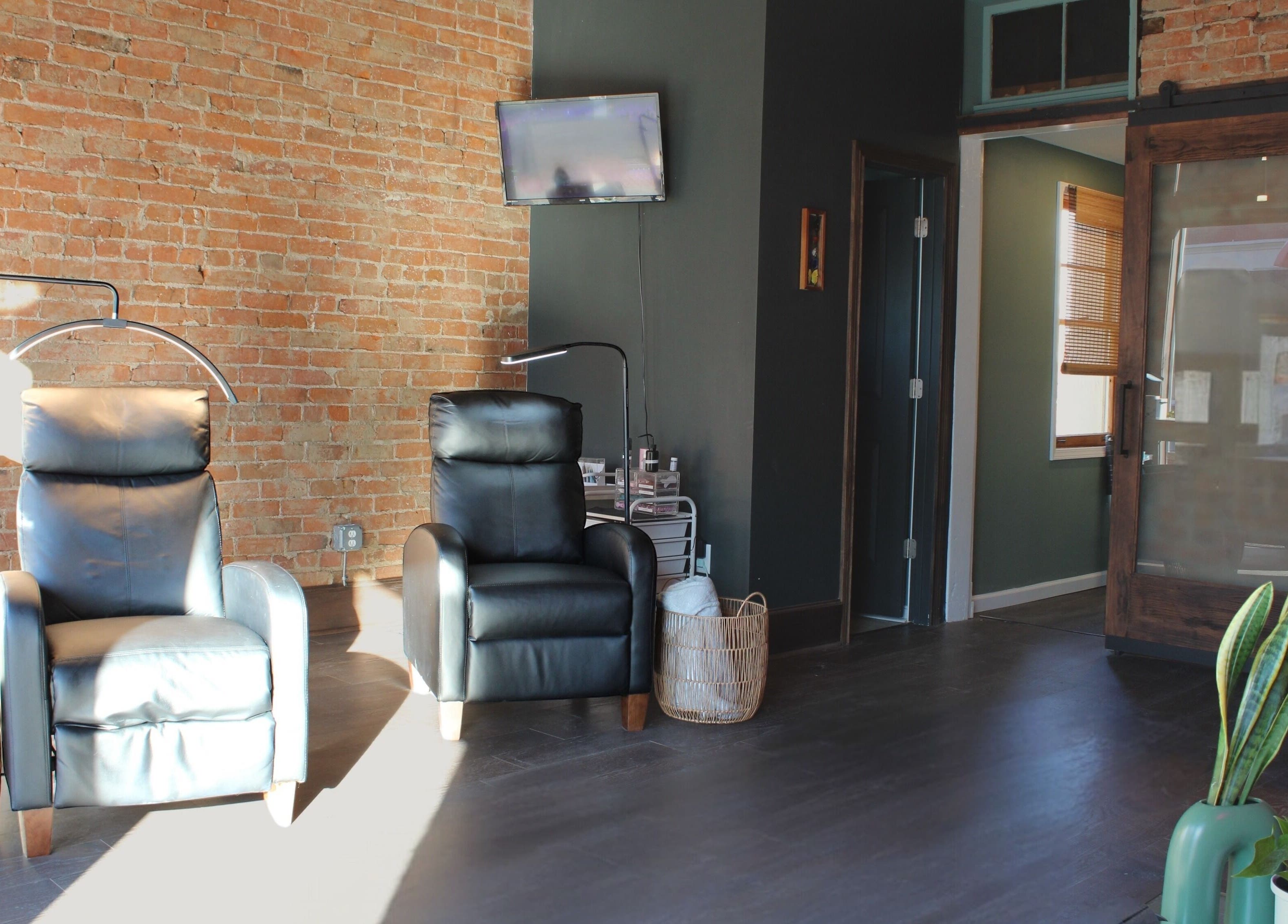 Modern and cozy seating at Orbit Esthetics, Covington, Kentucky, US with leather chairs and brick walls.