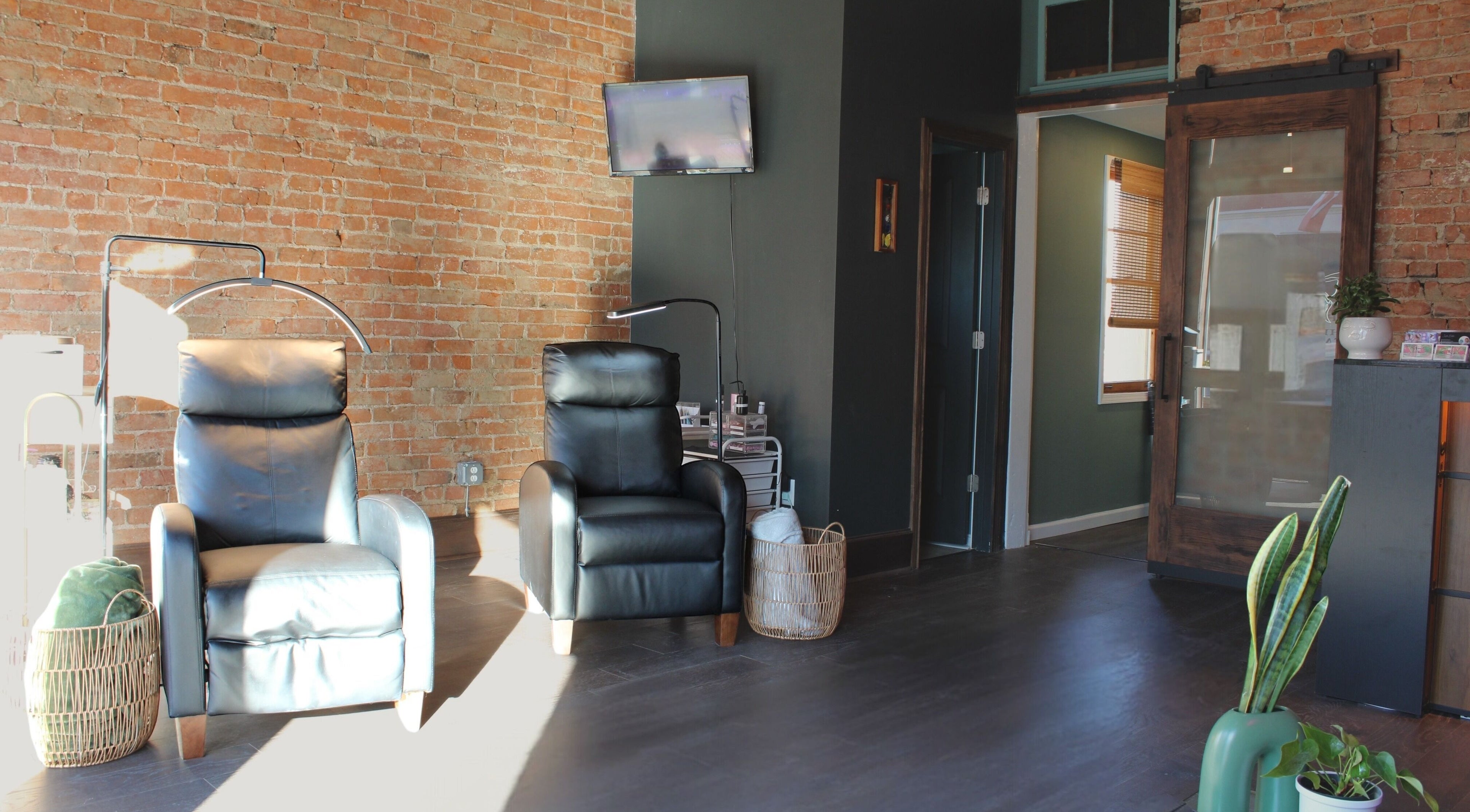 Modern and cozy seating at Orbit Esthetics, Covington, Kentucky, US with leather chairs and brick walls.