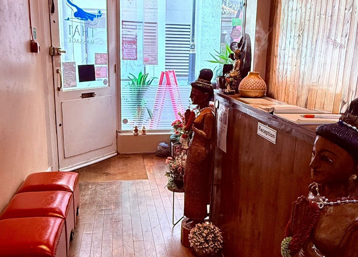 Entrance of Nisa Thai Spa near Buckingham Palace, showcasing wooden decor and statues in London, England, GB.