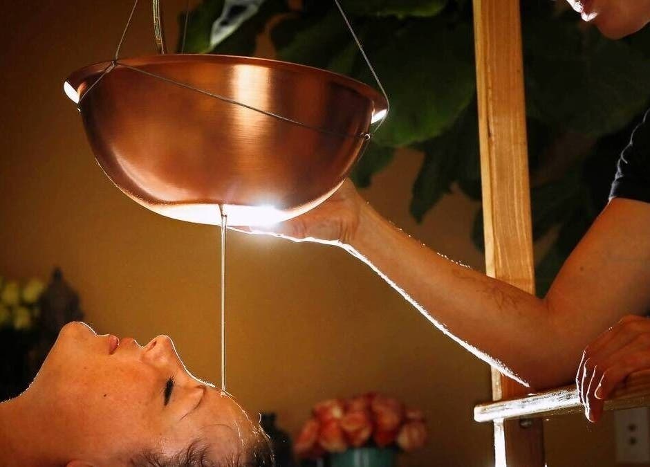 Ayurvedic therapy at KESALZ LLC in San Jose, California, US, showing a calming oil flow onto a client's forehead.