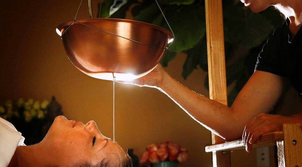 Ayurvedic therapy at KESALZ LLC in San Jose, California, US, showing a calming oil flow onto a client's forehead.