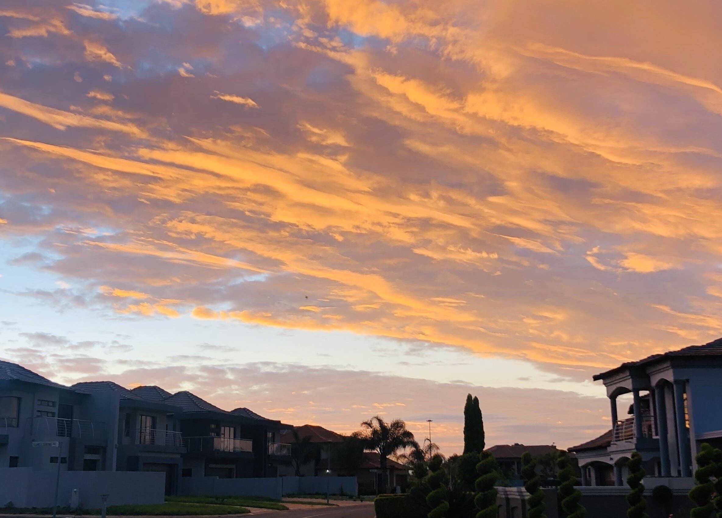 Beautiful sunset over homes near Glizzy Cuts, Pretoria, Gauteng, ZA, displaying vibrant skies.