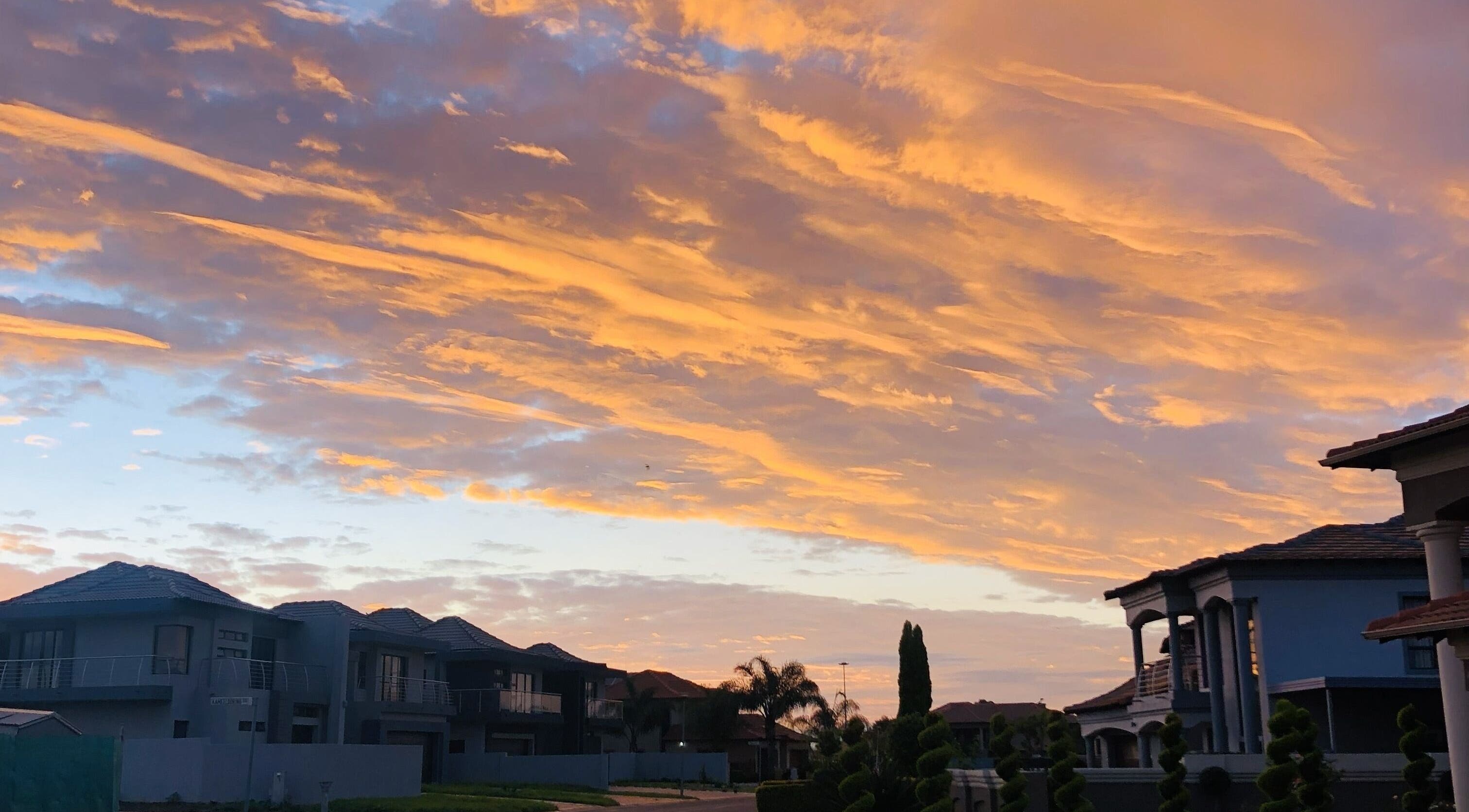 Beautiful sunset over homes near Glizzy Cuts, Pretoria, Gauteng, ZA, displaying vibrant skies.