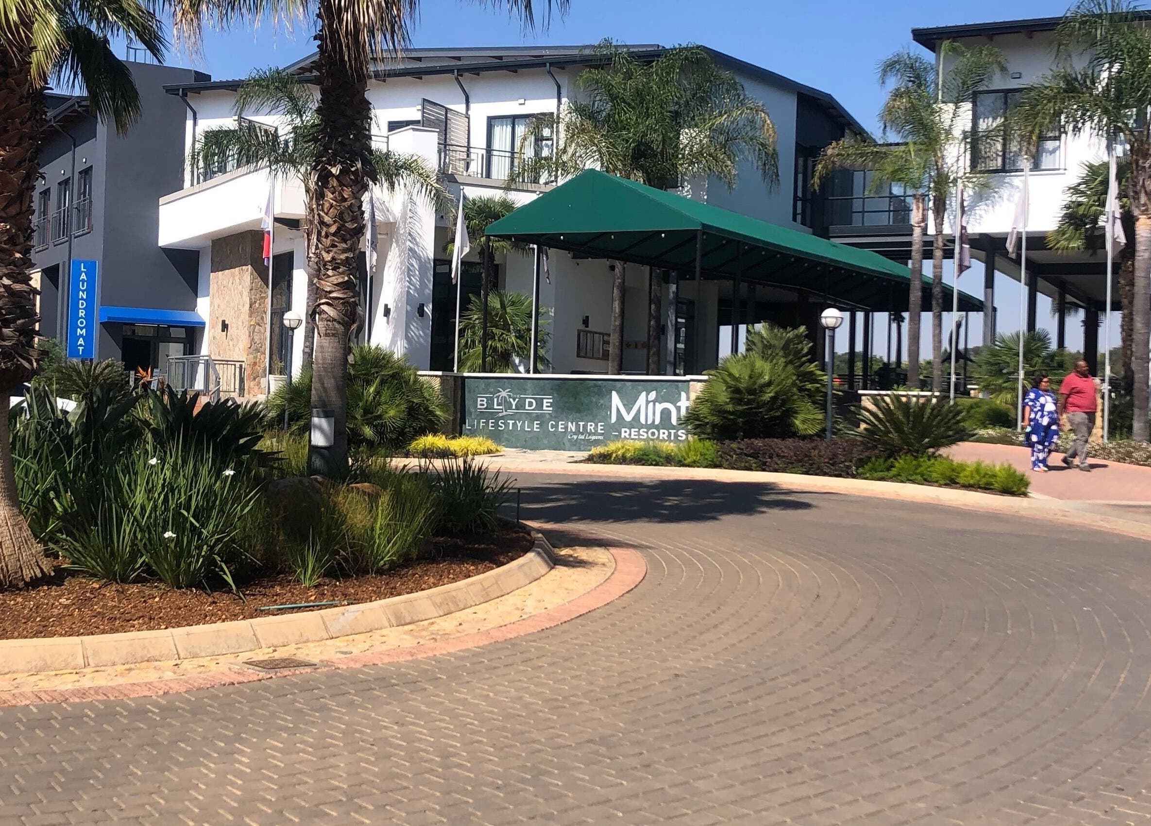 Entrance to Blyde Lifestyle Centre near Glizzy Cuts, Pretoria, Gauteng, ZA amid lush greenery.