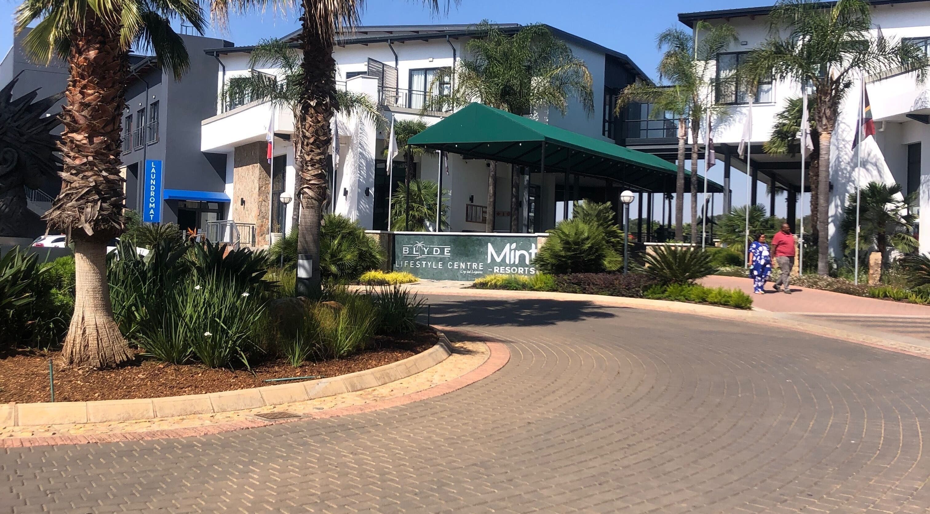 Entrance to Blyde Lifestyle Centre near Glizzy Cuts, Pretoria, Gauteng, ZA amid lush greenery.