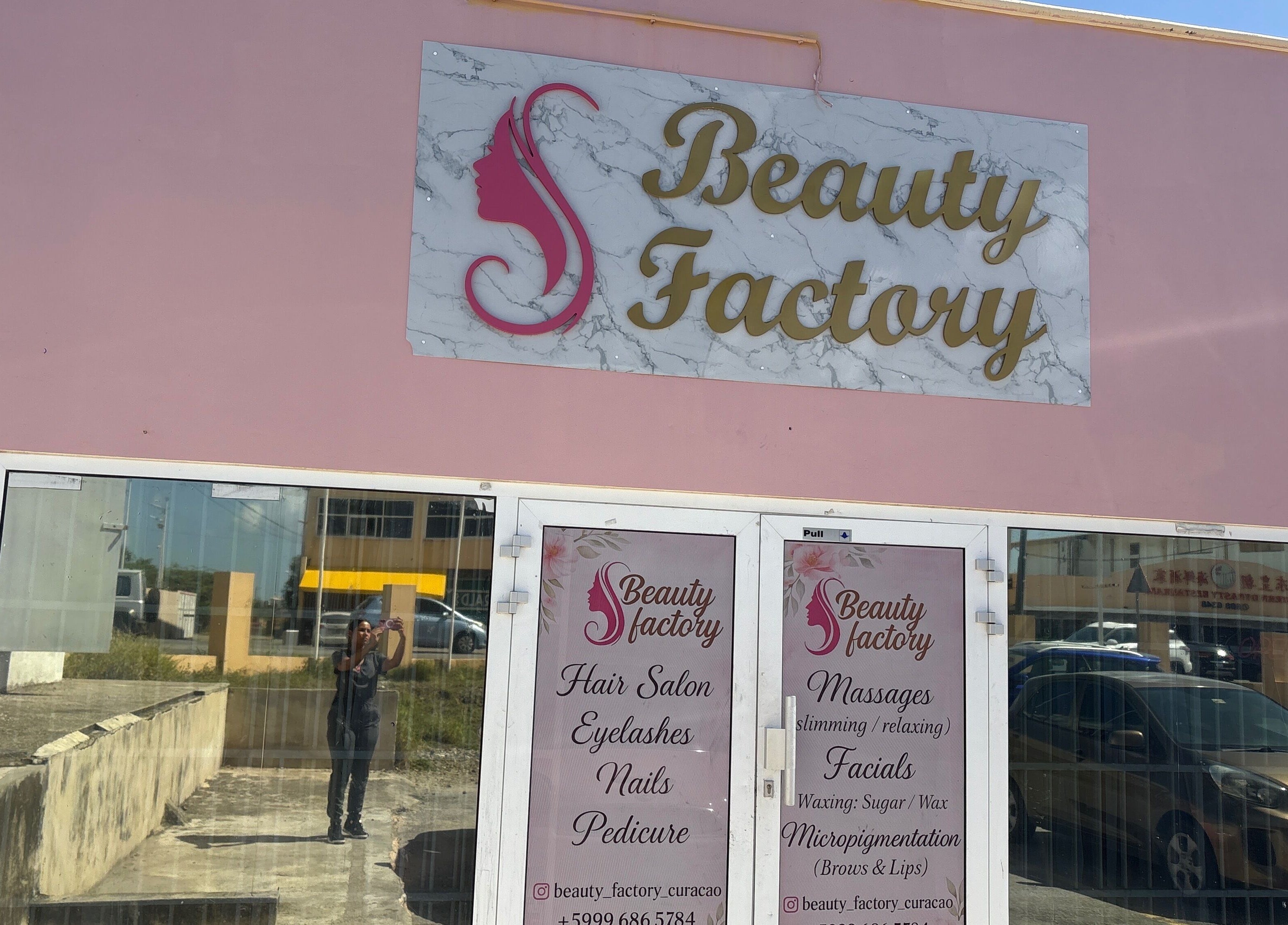 Fachada de Beautyfactorycuracao en Willemstad, Curaçao, CW con cartel rosa y blanco sobre puerta de vidrio.