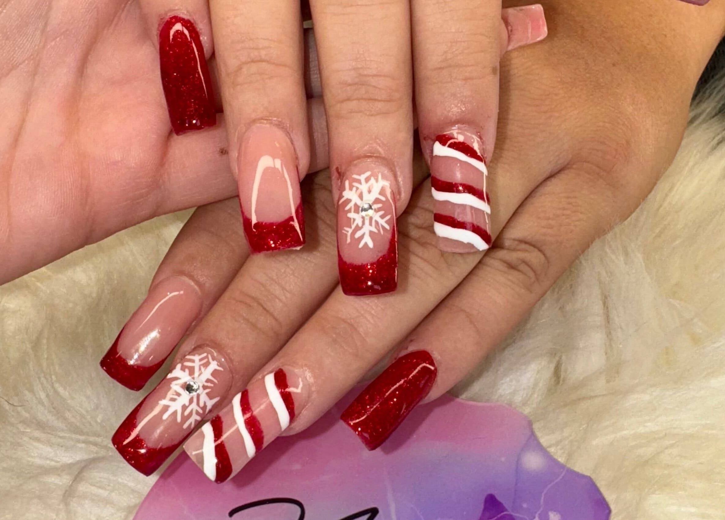 Festive red and white nail art at The Cass Effect in Deland, Florida, US, featuring intricate snowflake designs.