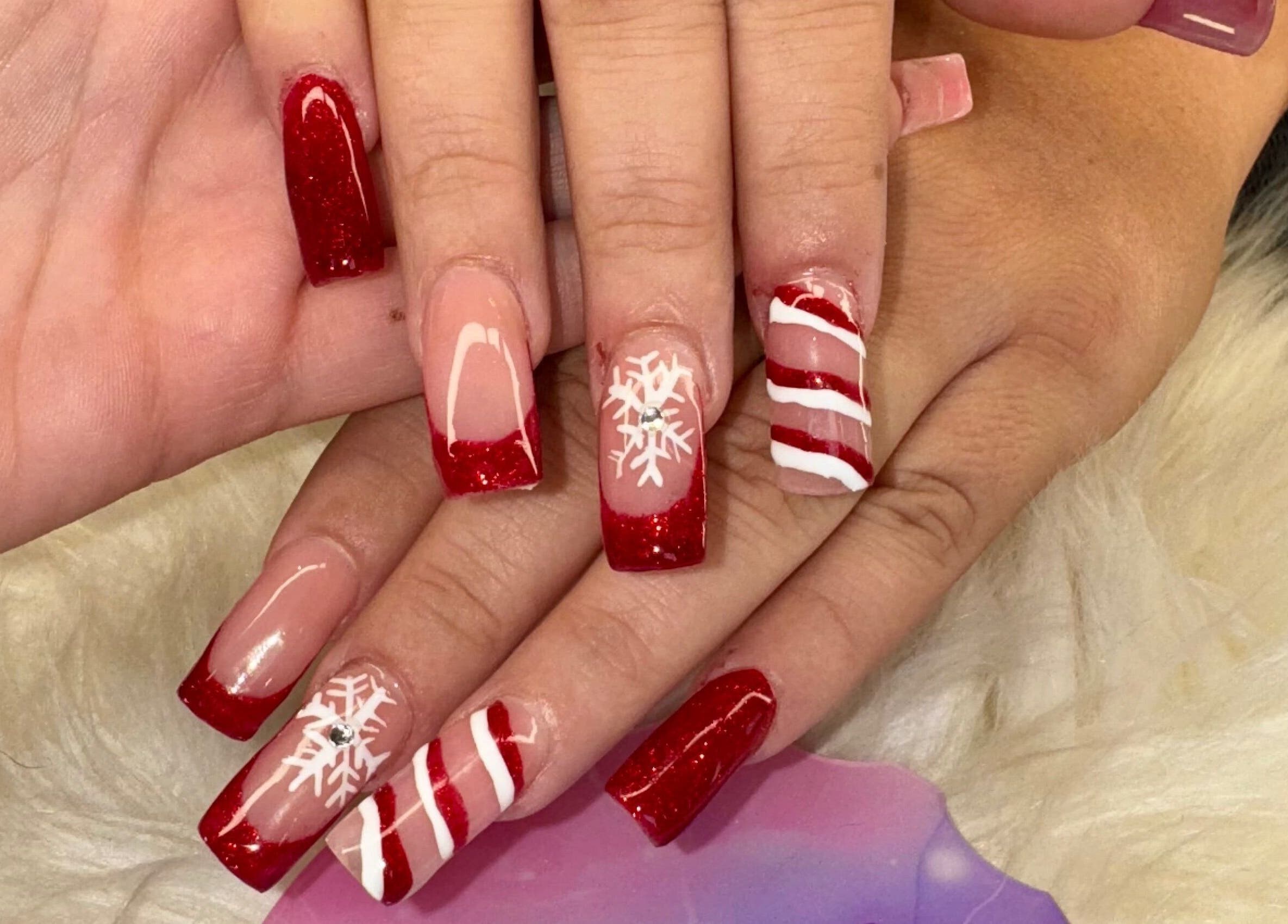Festive holiday nail art at The Cass Effect, Deland, Florida, US, featuring red glitter and snowflakes.