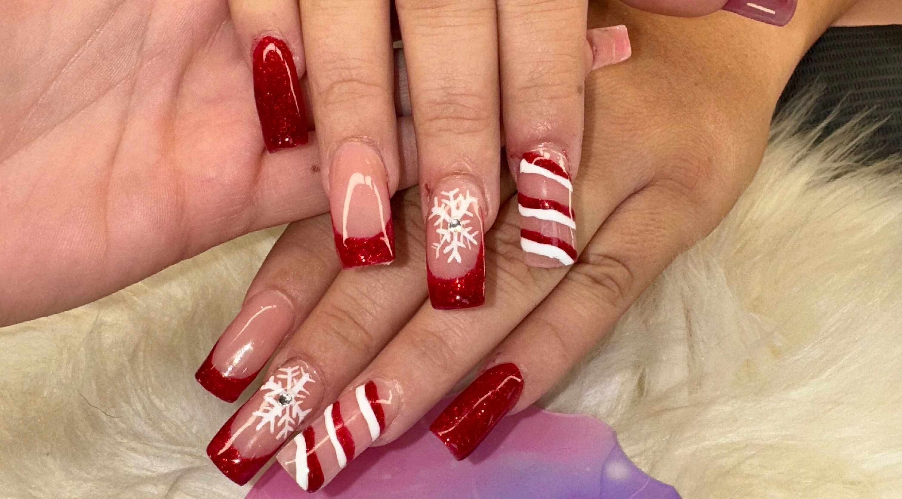 Festive holiday nail art at The Cass Effect, Deland, Florida, US, featuring red glitter and snowflakes.