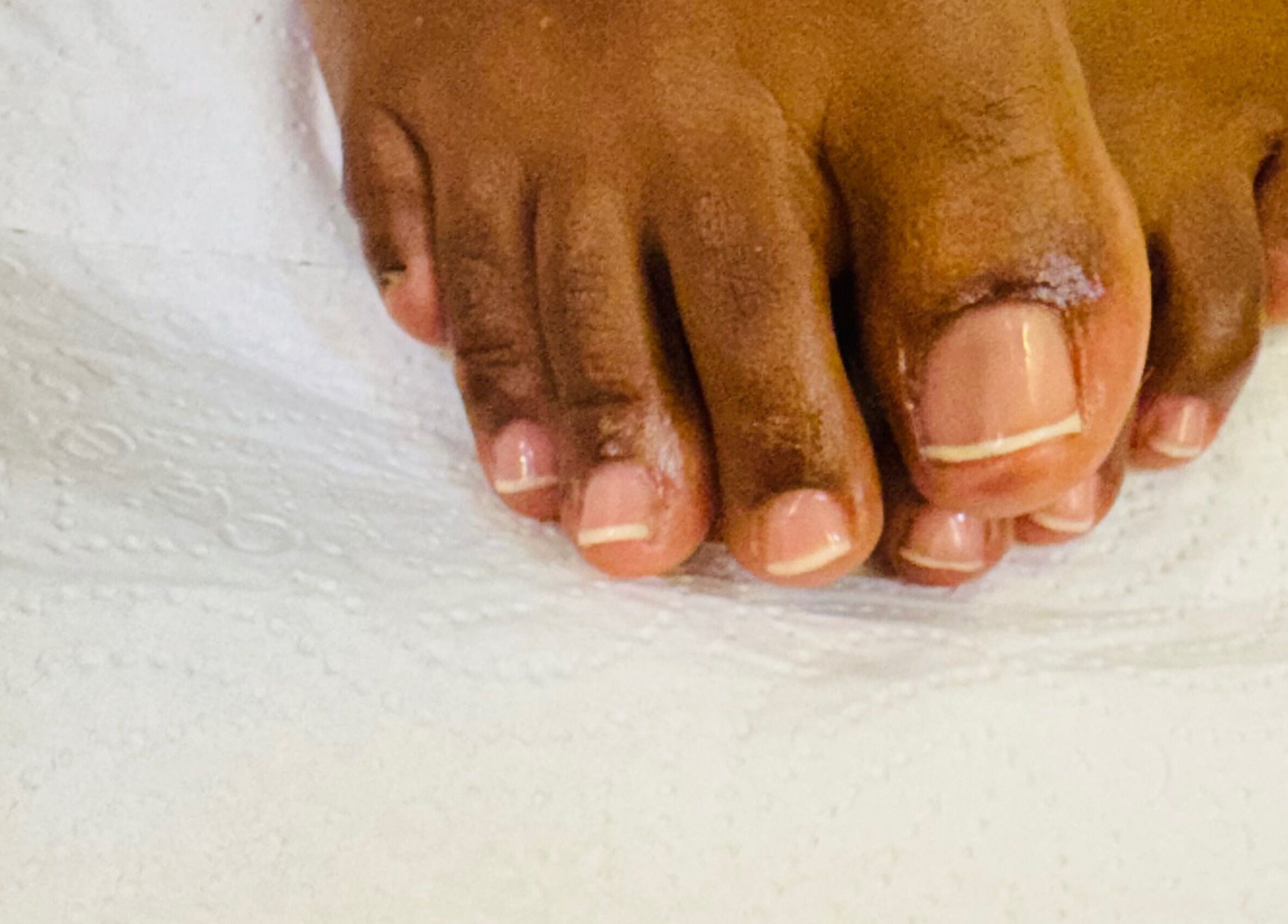 Freshly pedicured toes from Pure Glow Mani And Pedi Mobile, Cape Town, Western Cape, ZA on white paper towel.