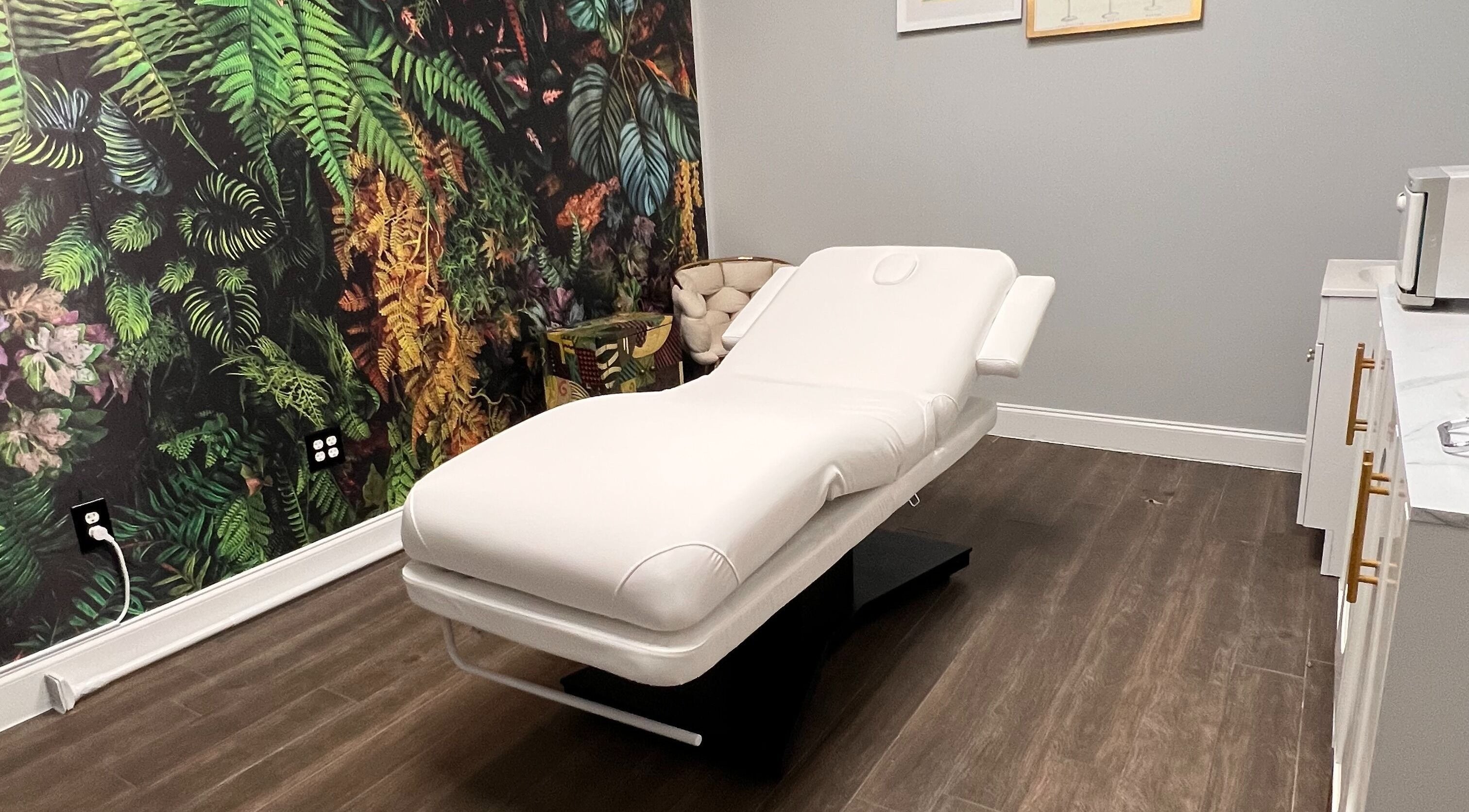 Chic spa treatment room at THE REVIVE BAR in Allen, Texas, US with a plush white bed and botanical wall.