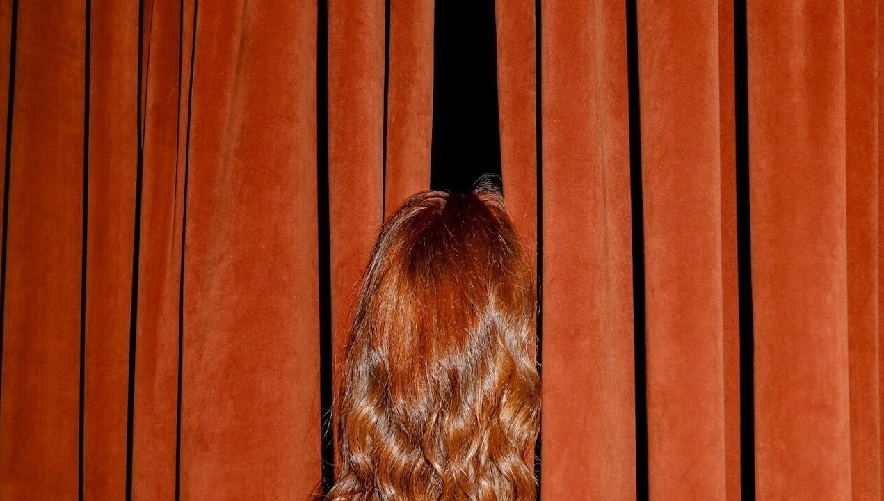 CRYBABY HAIRCLUB in Glasgow showcases vibrant red hair peeking through elegant velvet curtains.