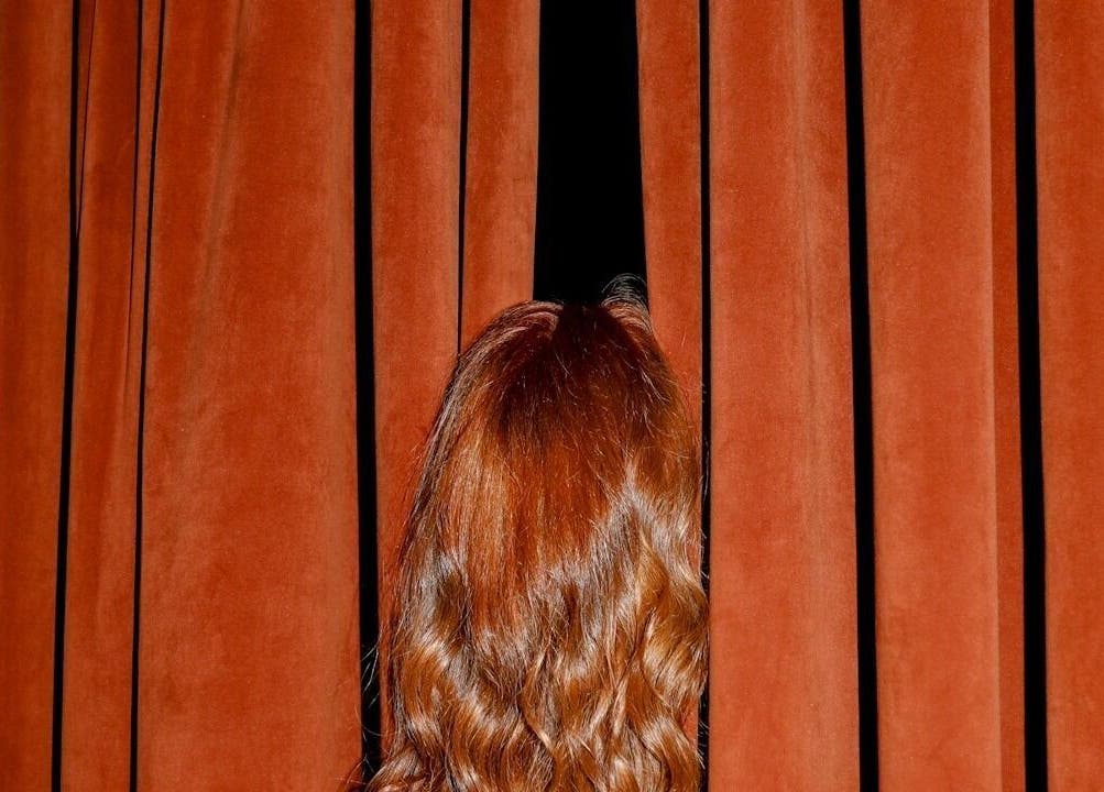 CRYBABY HAIRCLUB in Glasgow showcases vibrant red hair peeking through elegant velvet curtains.