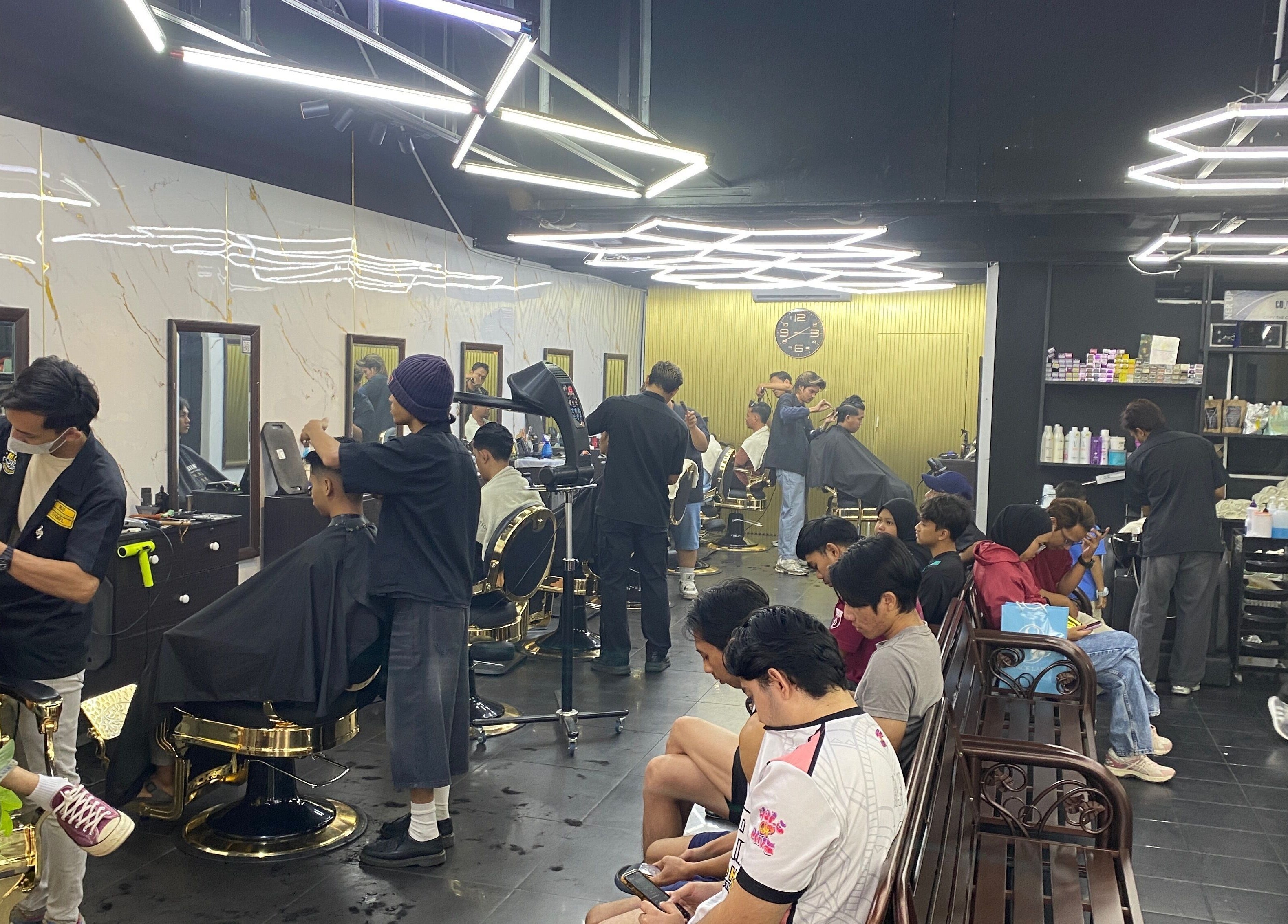 Barbers busy styling at MCo Barbershop Hq, Shah Alam, Selangor, MY, with a modern interior and clients waiting.