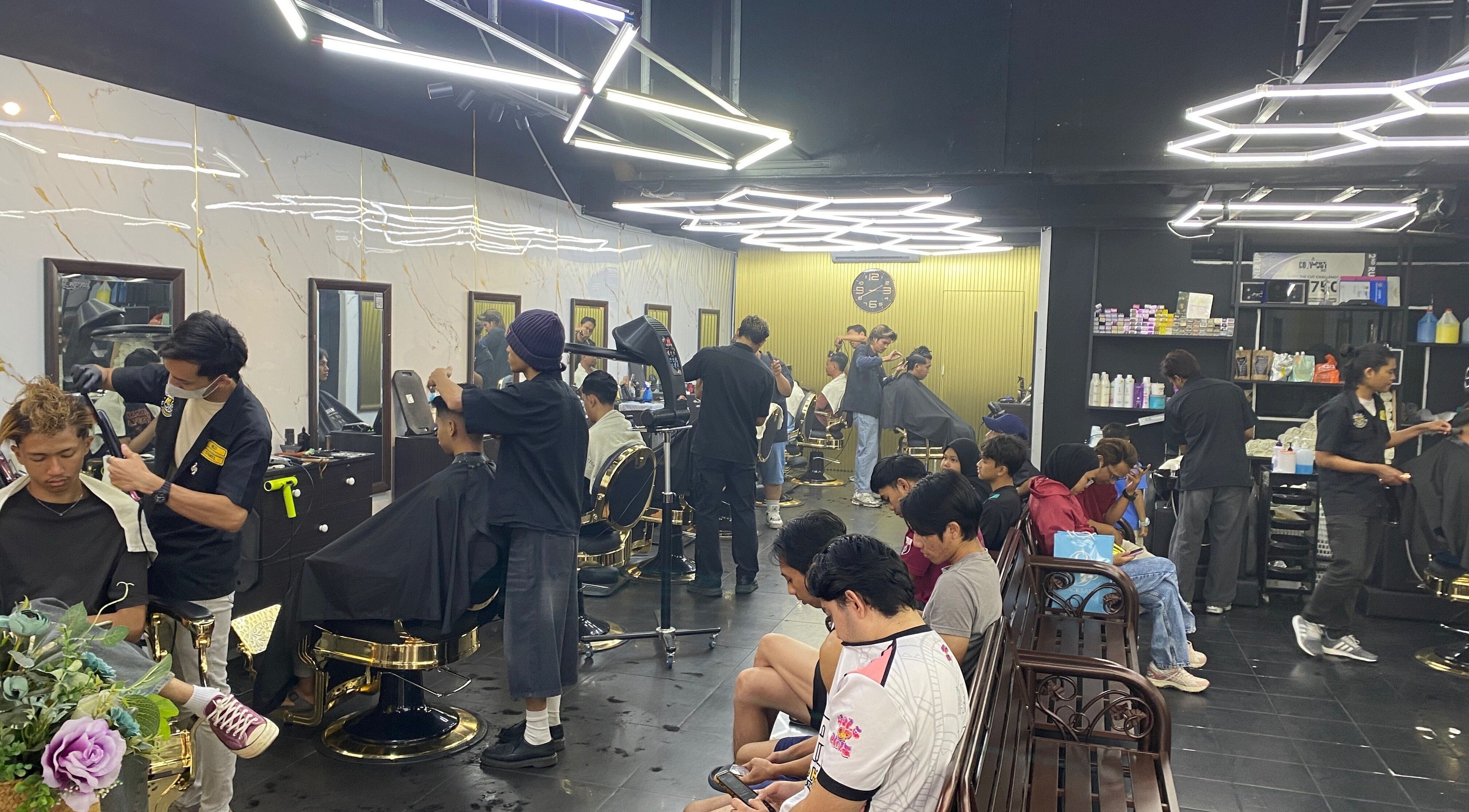 Barbers busy styling at MCo Barbershop Hq, Shah Alam, Selangor, MY, with a modern interior and clients waiting.