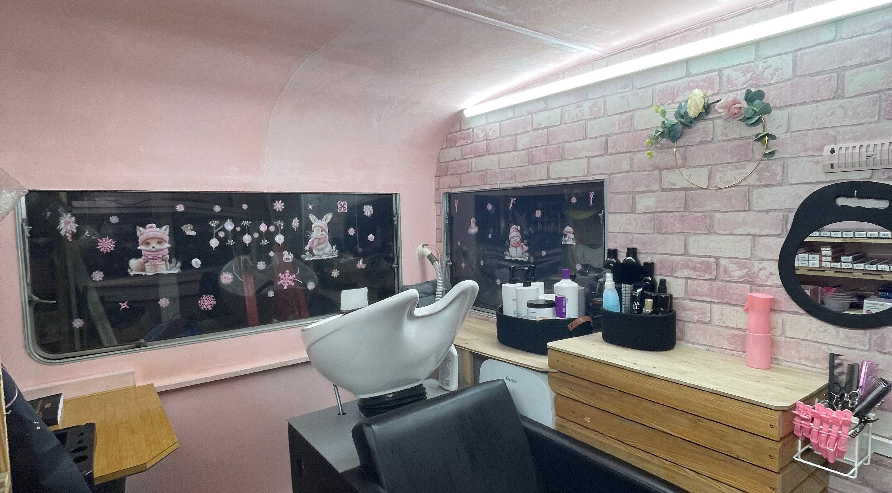 Intérieur de Le salon de Laura à Genneville, Normandie, FR avec décorations roses et poste de coiffure.