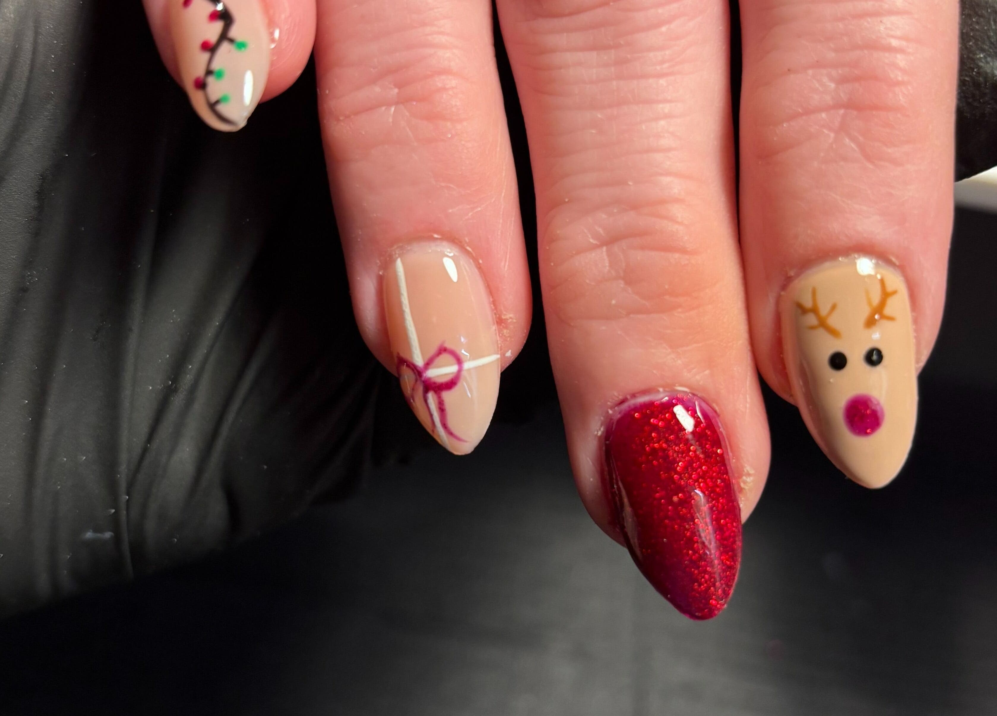 Holiday-themed nail art at Black Cat Nails in Long Lawford, England, GB features reindeer and gift designs.