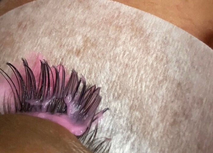 Close-up of a lash extension process at NĀSKIN, Cape Town, Western Cape, ZA with pink adhesive.