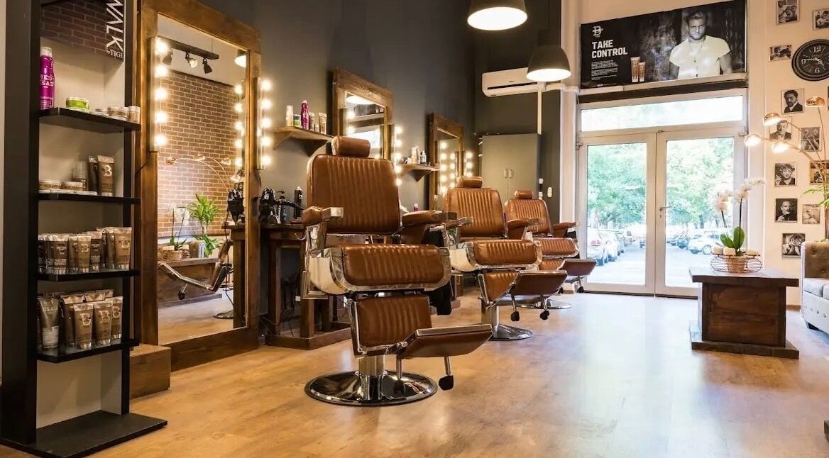 Modern salon interior at Cleancut, Budapest, Magyar, HU with leather chairs and lit mirrors.