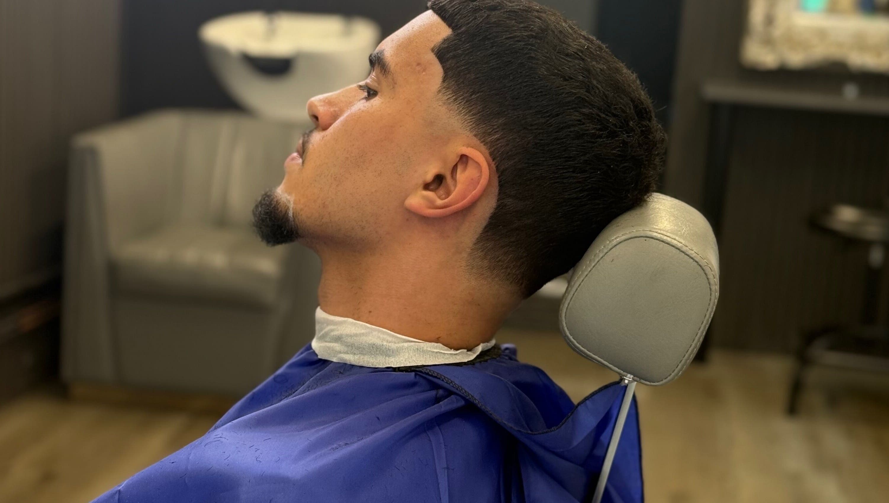 Modern haircut at Marlos barber in High Wycombe, England. Client with fresh fade and vibrant blue cape.