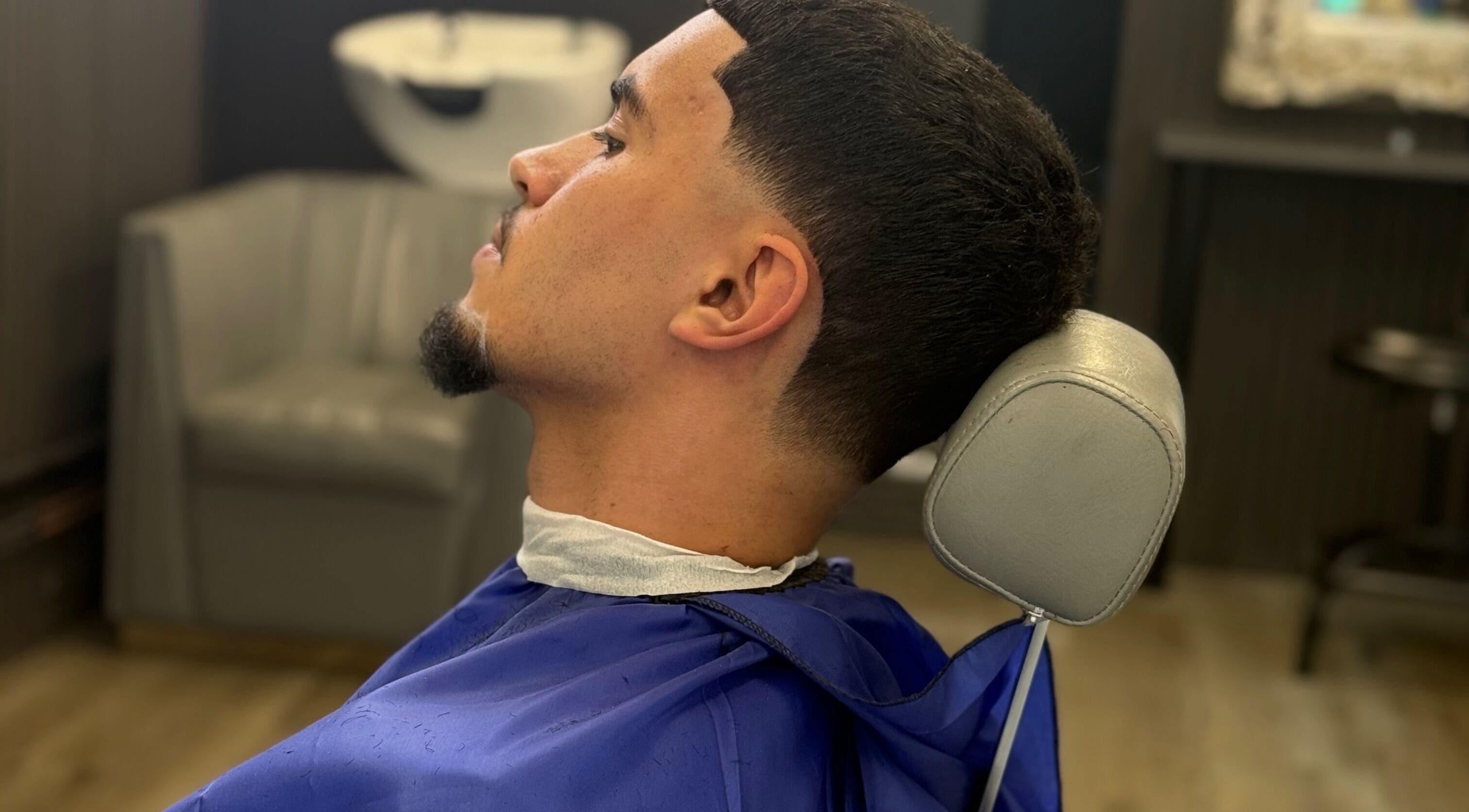 Modern haircut at Marlos barber in High Wycombe, England. Client with fresh fade and vibrant blue cape.