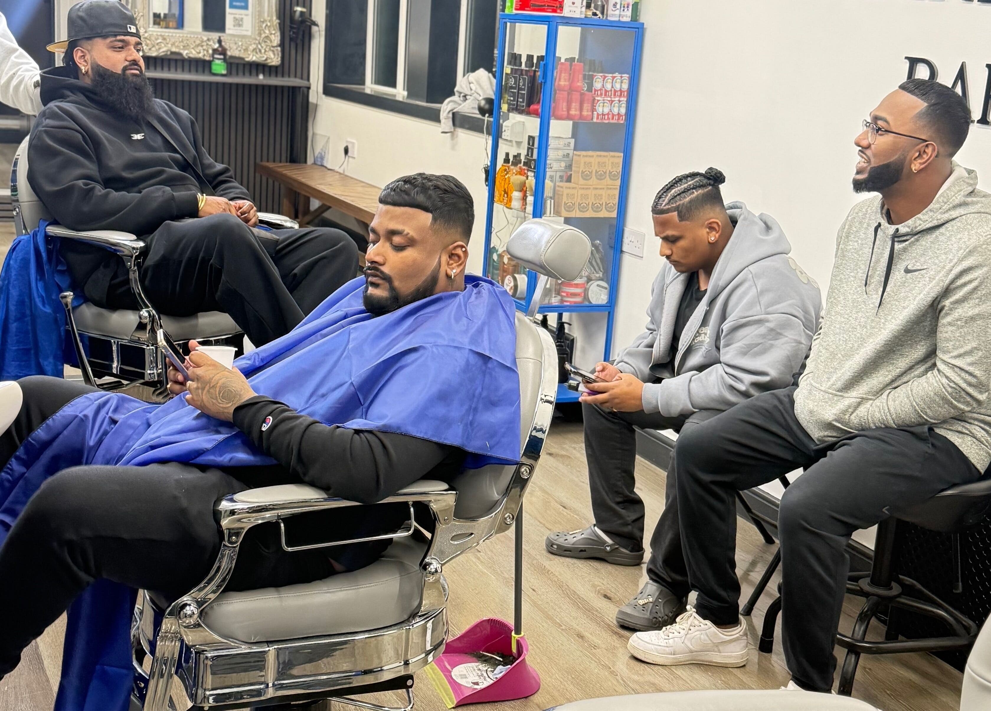 Relaxed clients at Marlos barber High Wycombe, England receiving stylish haircuts in a modern barbershop setting.