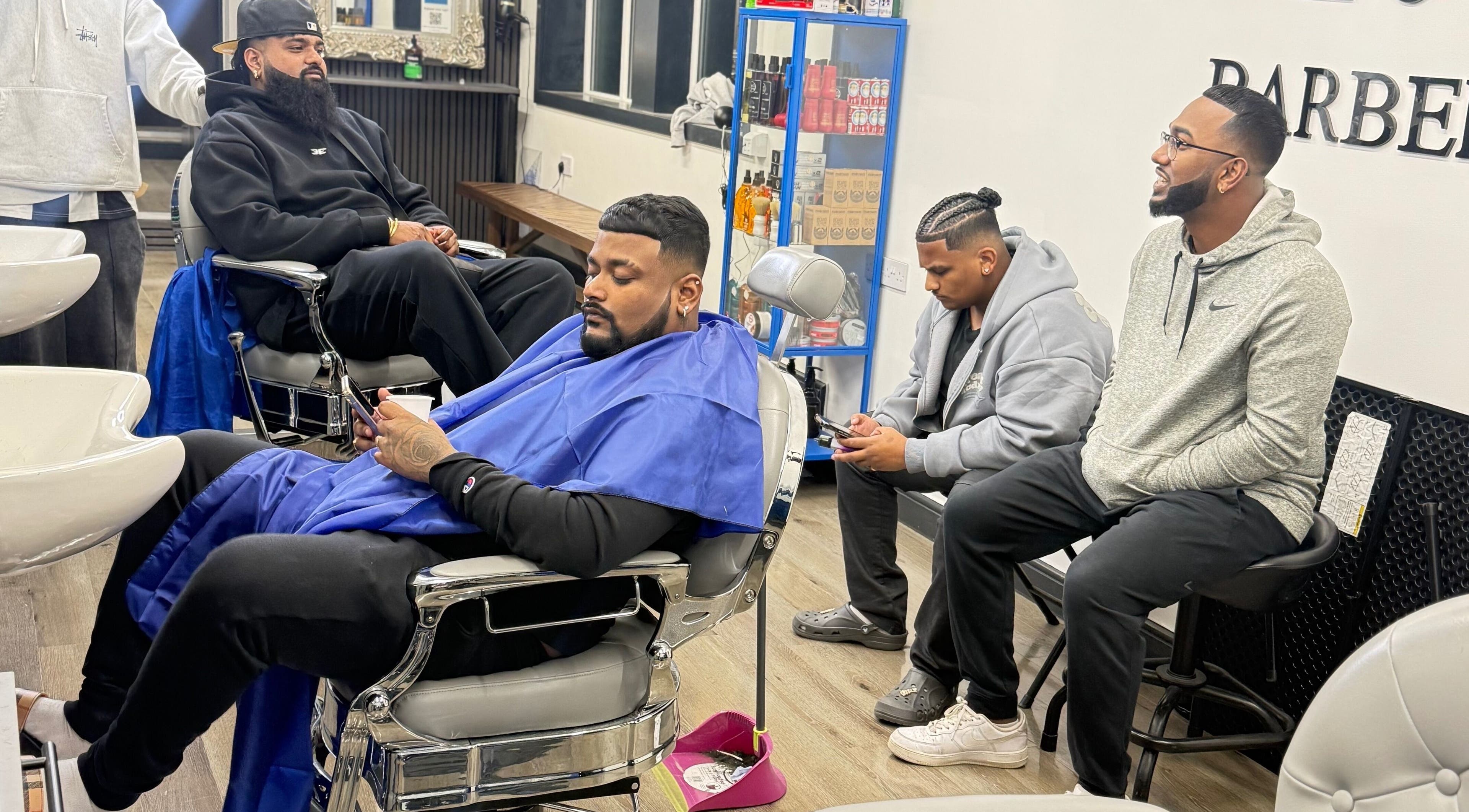 Relaxed clients at Marlos barber High Wycombe, England receiving stylish haircuts in a modern barbershop setting.