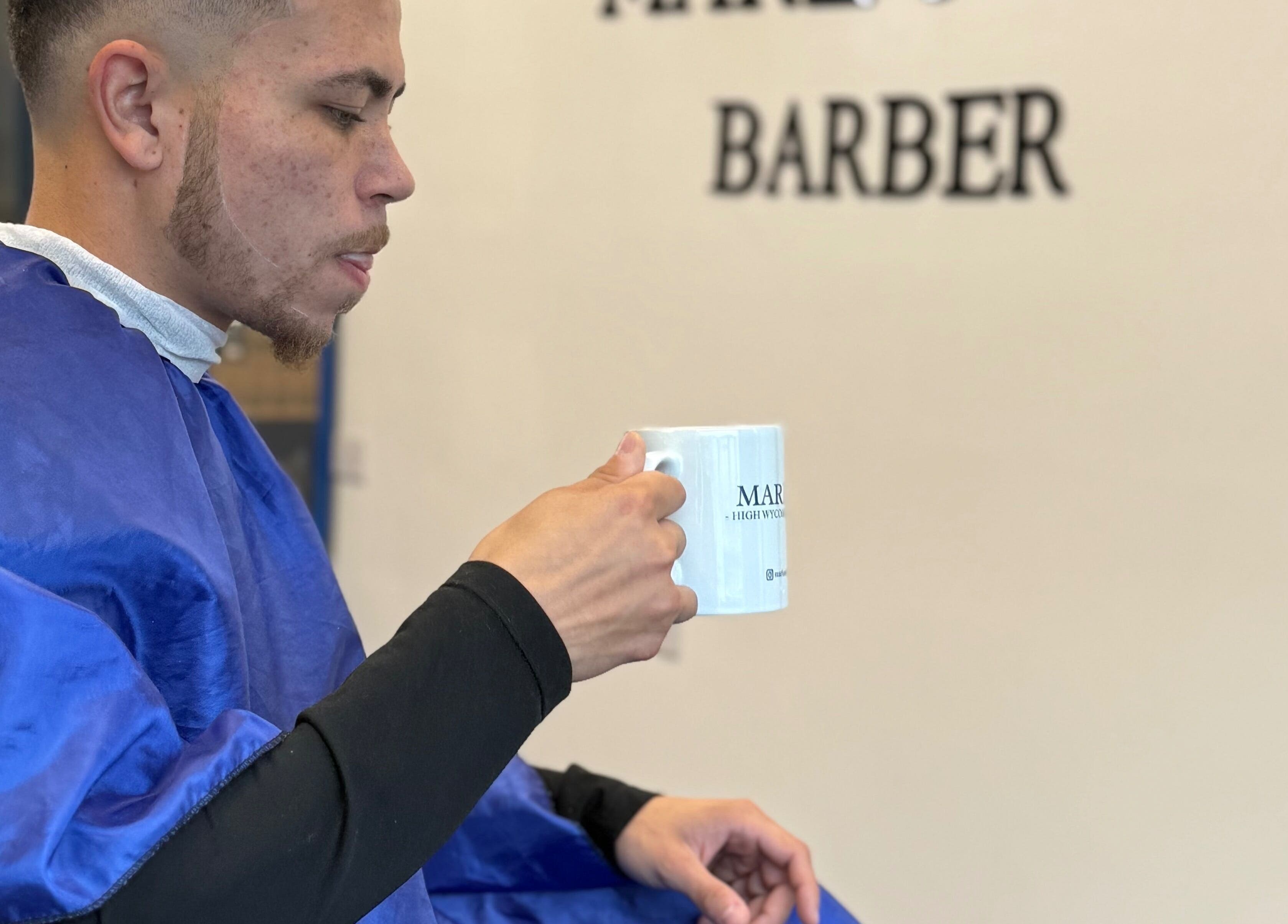 Client enjoying coffee at Marlos barber High Wycombe, England, GB before haircut, showcasing relaxed atmosphere.