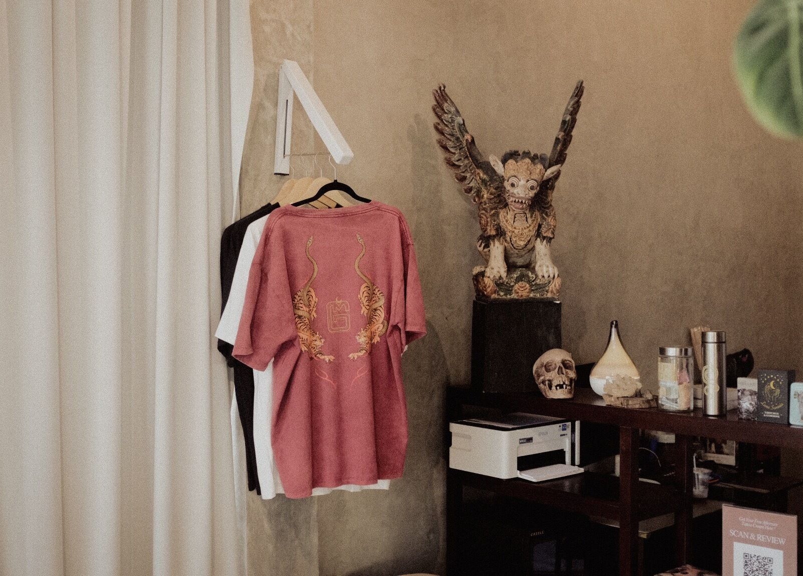 Interior of Galerimikro Tattoo Studio in Bali featuring unique decor including a sculpture and displayed shirts.