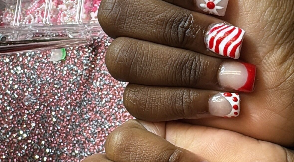 PolishedByQ in Beltsville, Maryland, US showcases festive red and white nail art over glitter background.