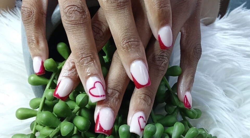 Stylish heart nail art at LuxeBeautyParlour, Centurion, Gauteng, ZA. Captivating red accents on manicured nails.