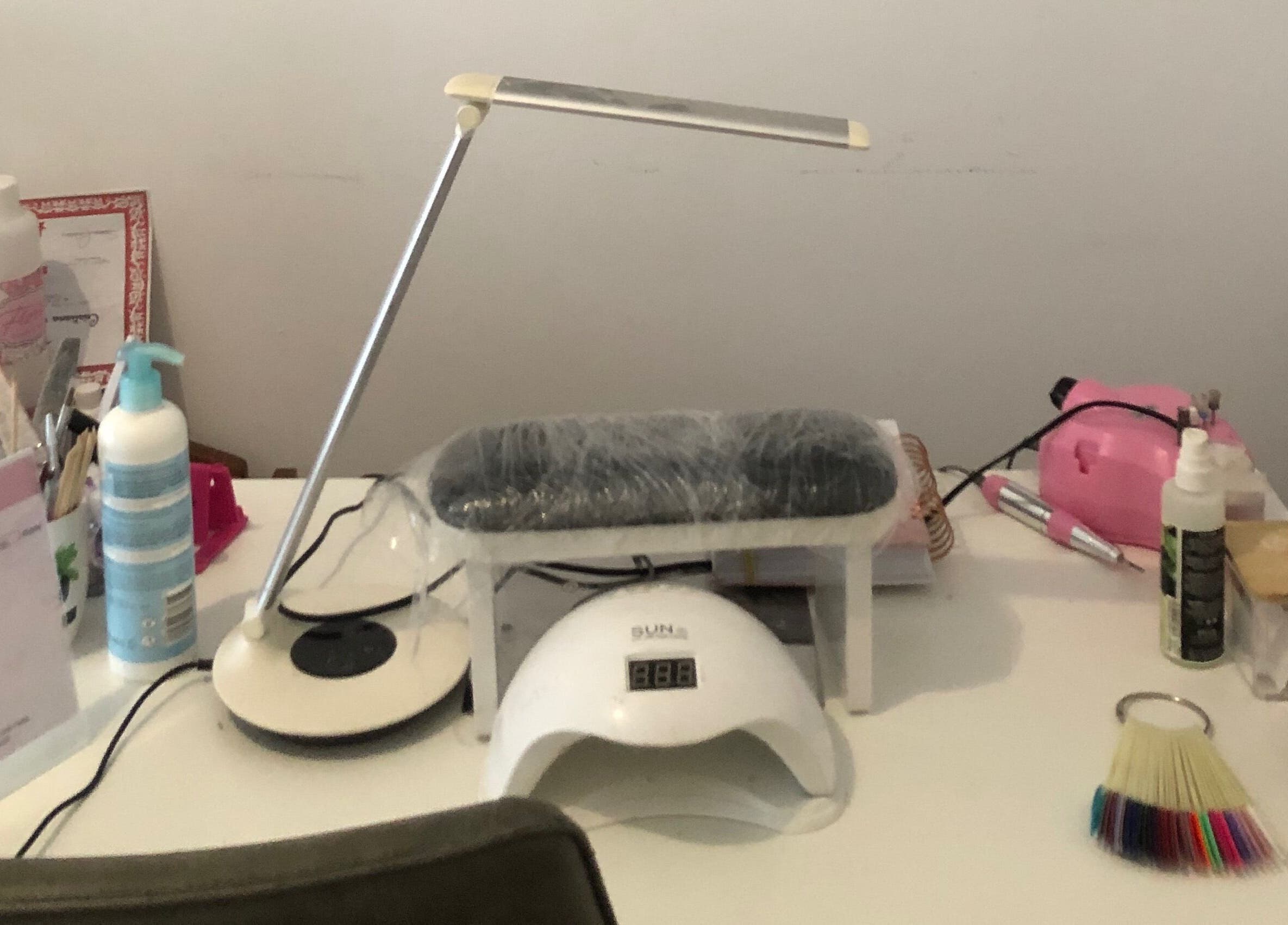 Nail care setup at Nails cris in Camarate, Lisboa, PT featuring tools, lamp, and sanitizer.