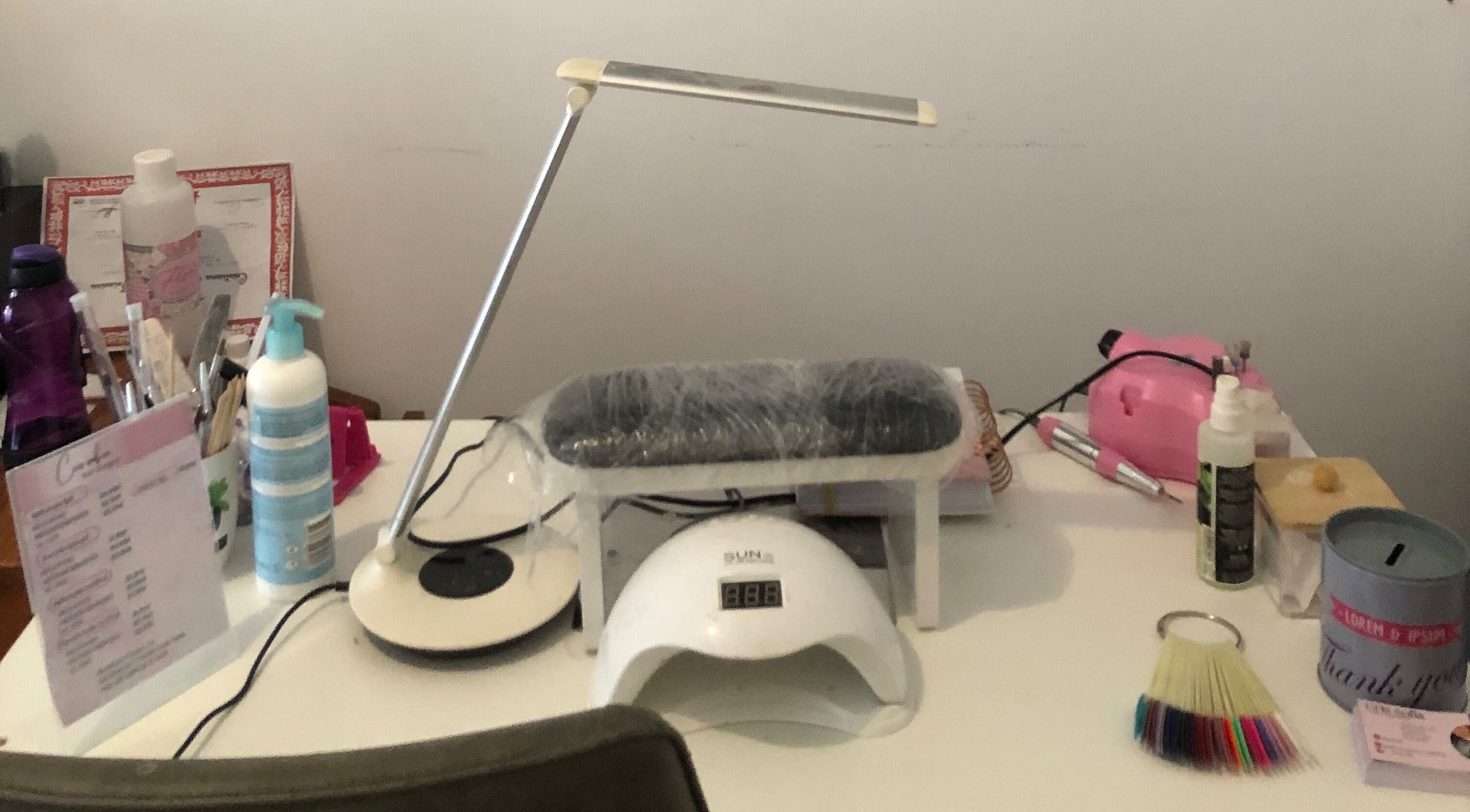 Nail care setup at Nails cris in Camarate, Lisboa, PT featuring tools, lamp, and sanitizer.