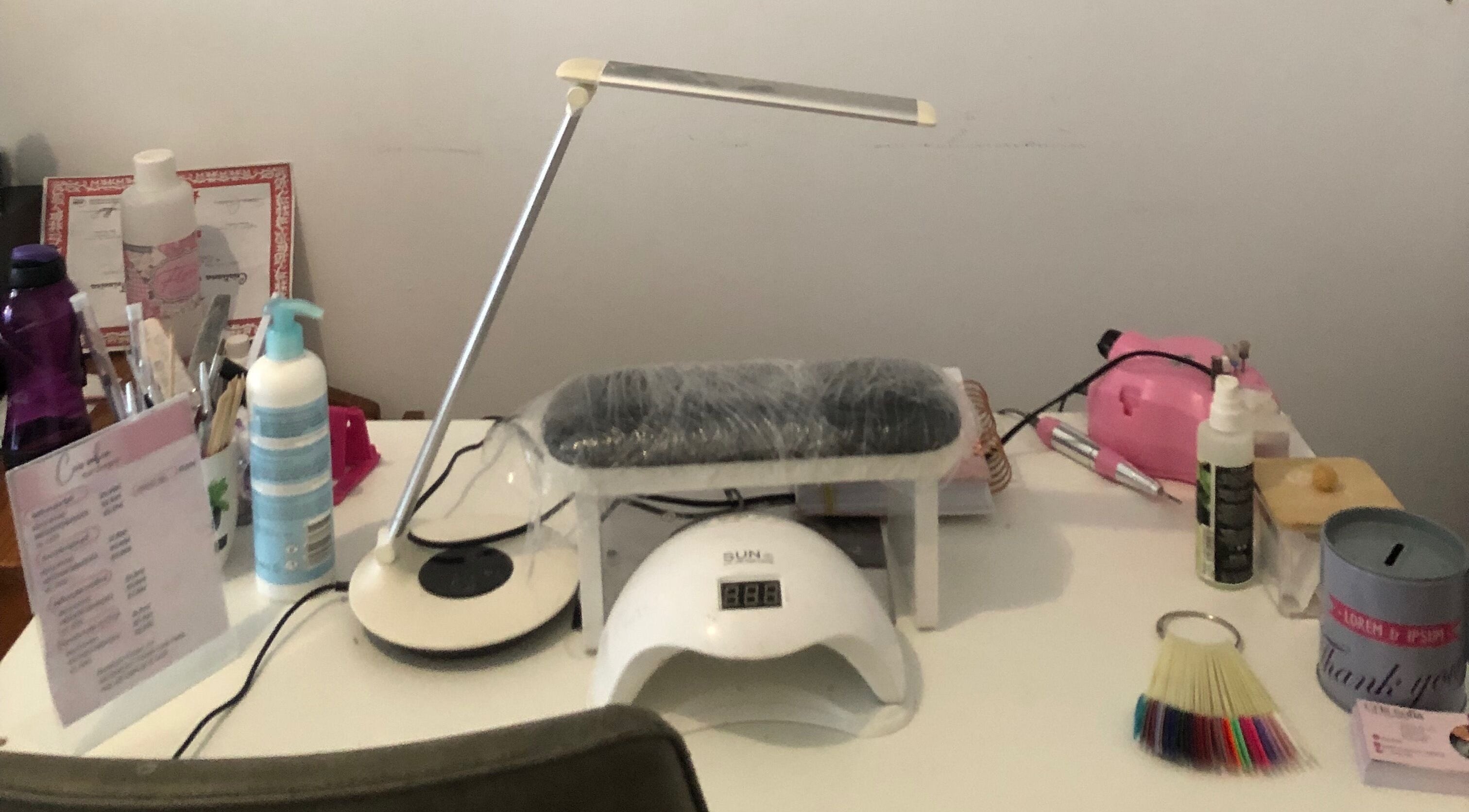 Nail care setup at Nails cris in Camarate, Lisboa, PT featuring tools, lamp, and sanitizer.
