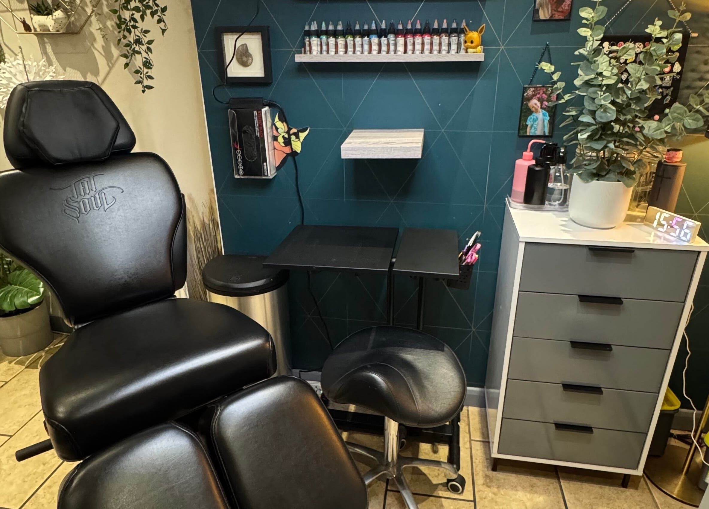 Sarah K Tattooist workspace in Birmingham, England, featuring a chair and ink shelf in a modern setting.