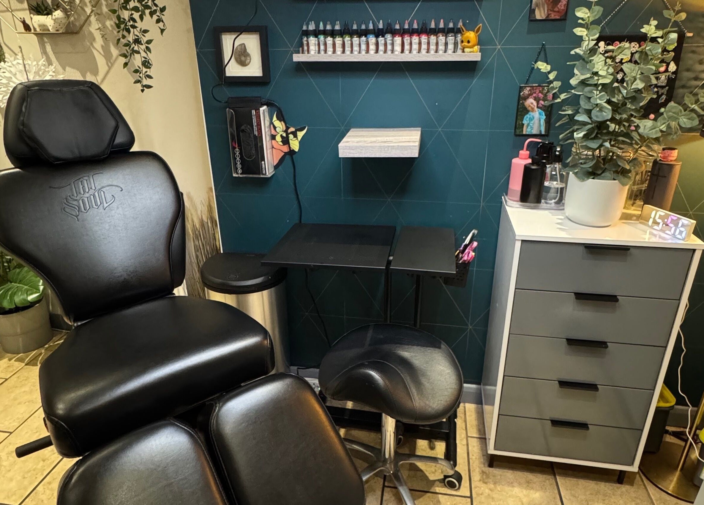 Sarah K Tattooist workspace in Birmingham, England, featuring a chair and ink shelf in a modern setting.