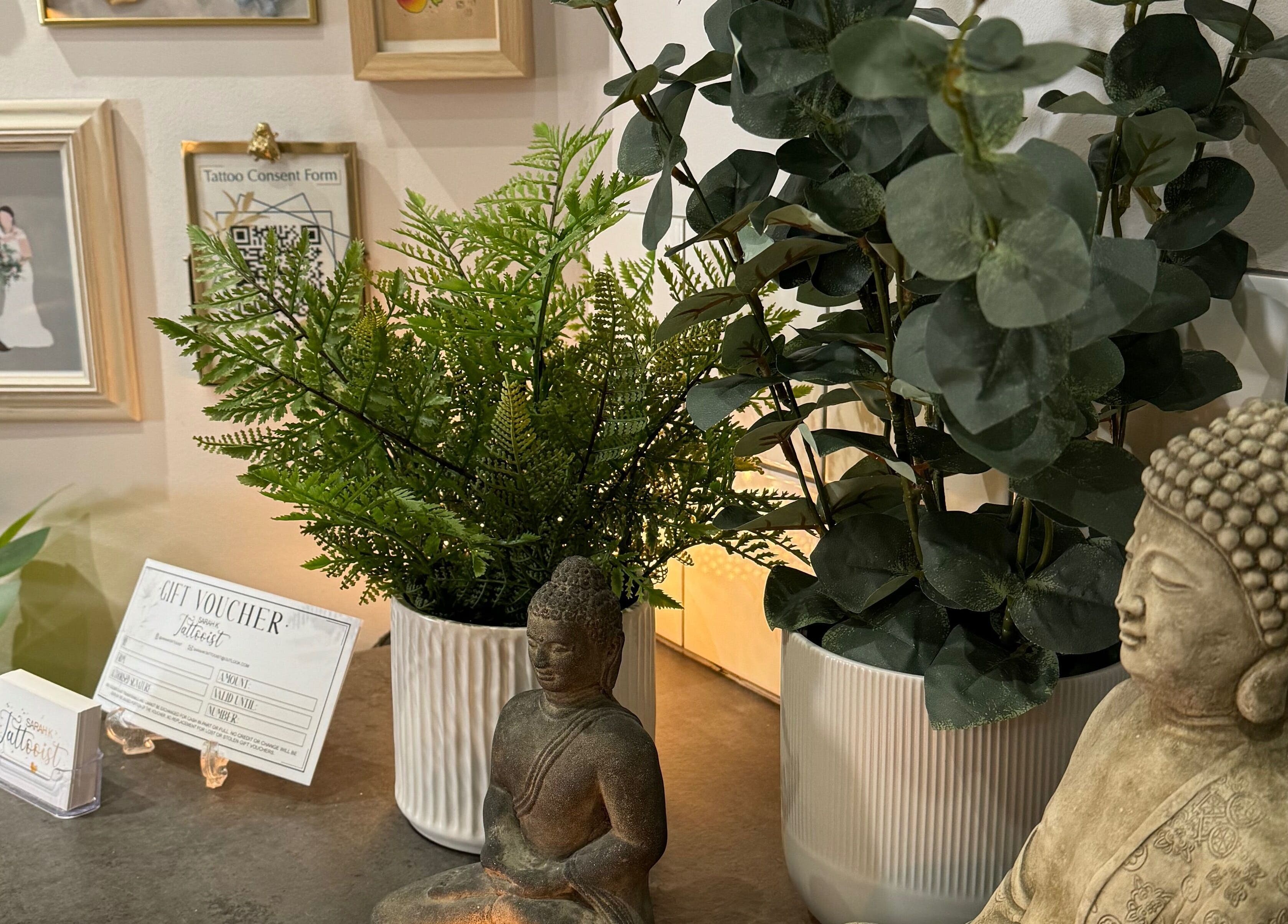 Serene decor at Sarah K Tattooist, Birmingham, England, GB, featuring plants and a Buddha statue.