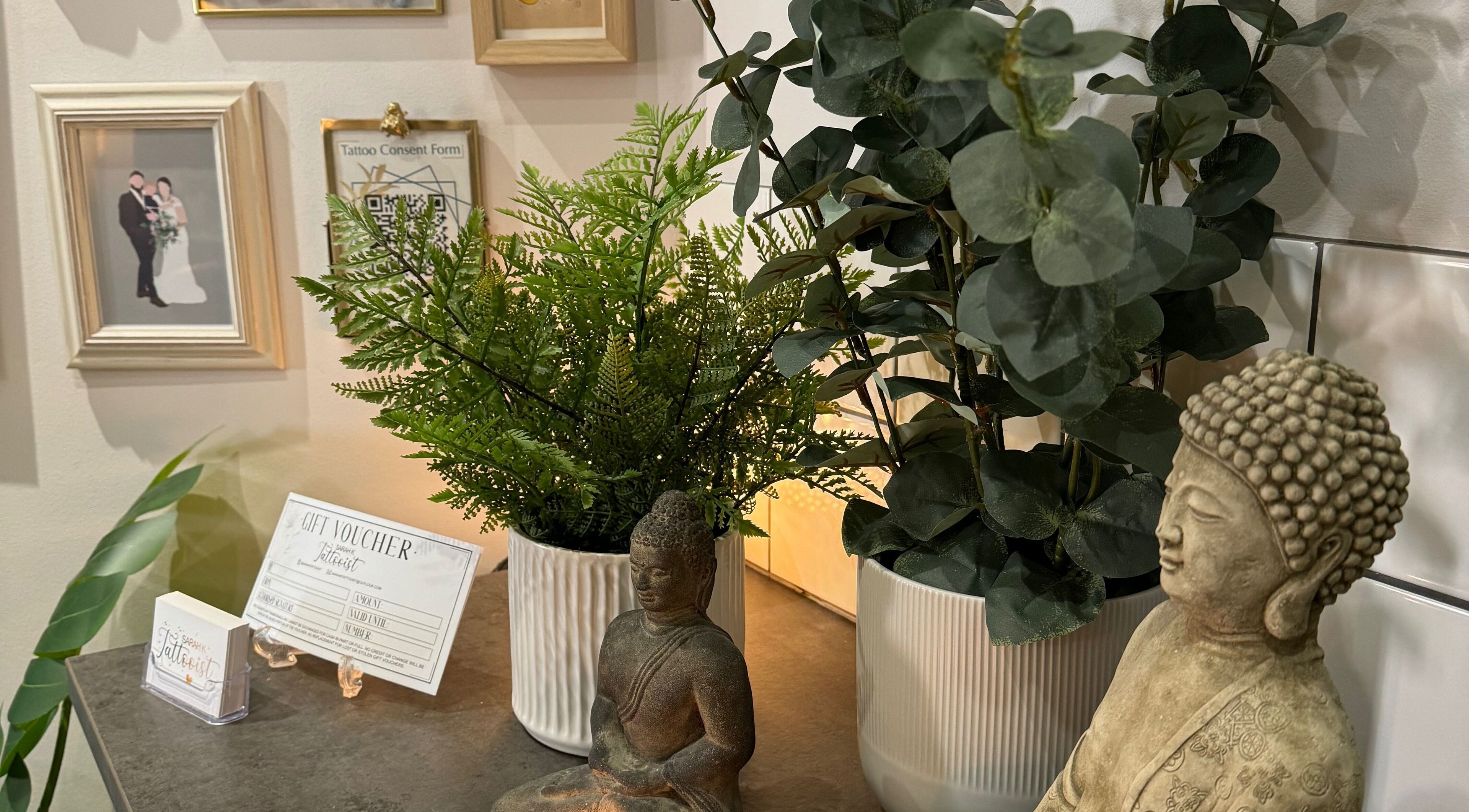 Serene decor at Sarah K Tattooist, Birmingham, England, GB, featuring plants and a Buddha statue.