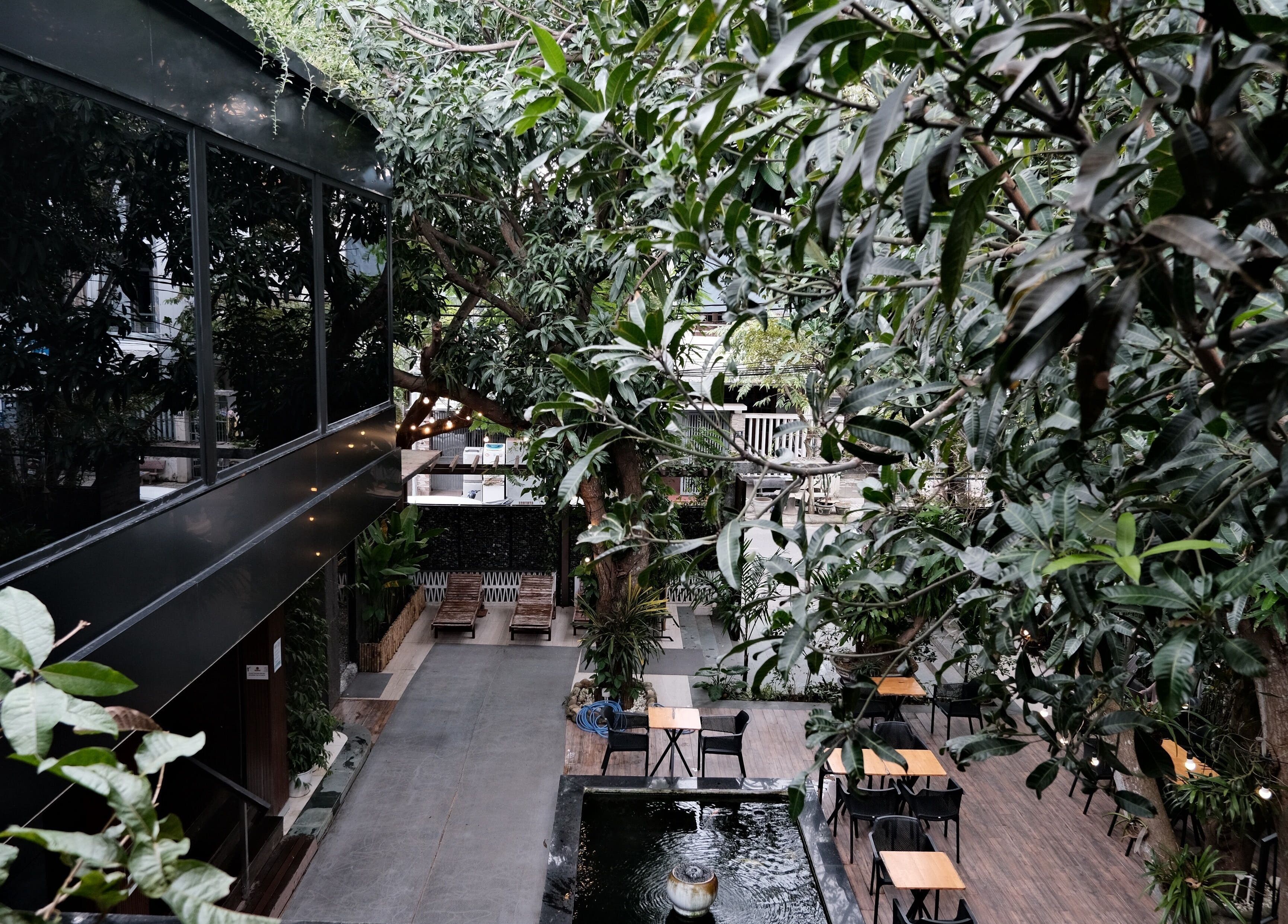 Lush green courtyard at Recharged SPA, Đà Nẵng, VN, featuring seating and a tranquil water feature.