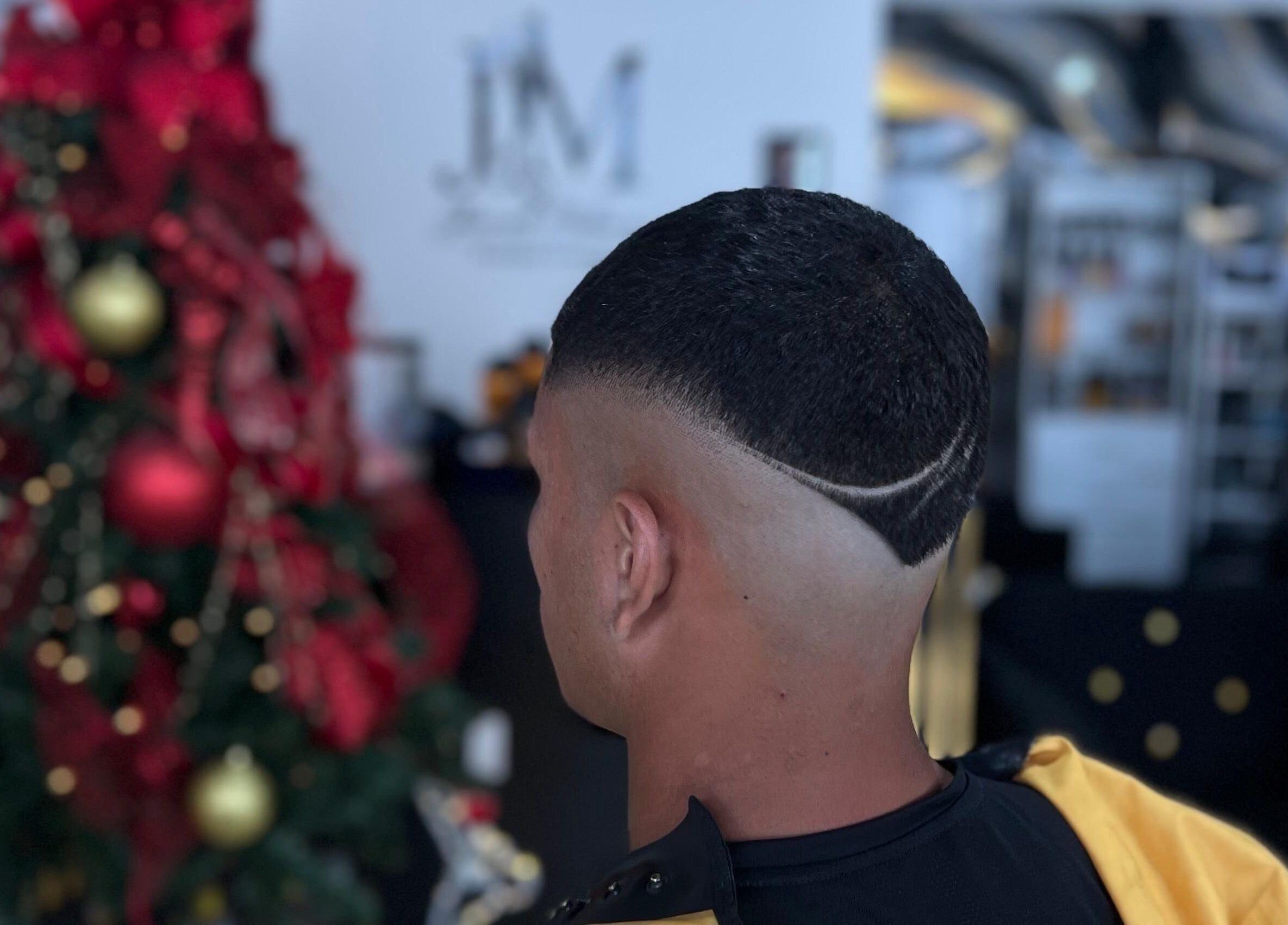 Intricate fade haircut at Hache Barber, Panamá, Provincia De Panamá, PA, near a festive Christmas tree.