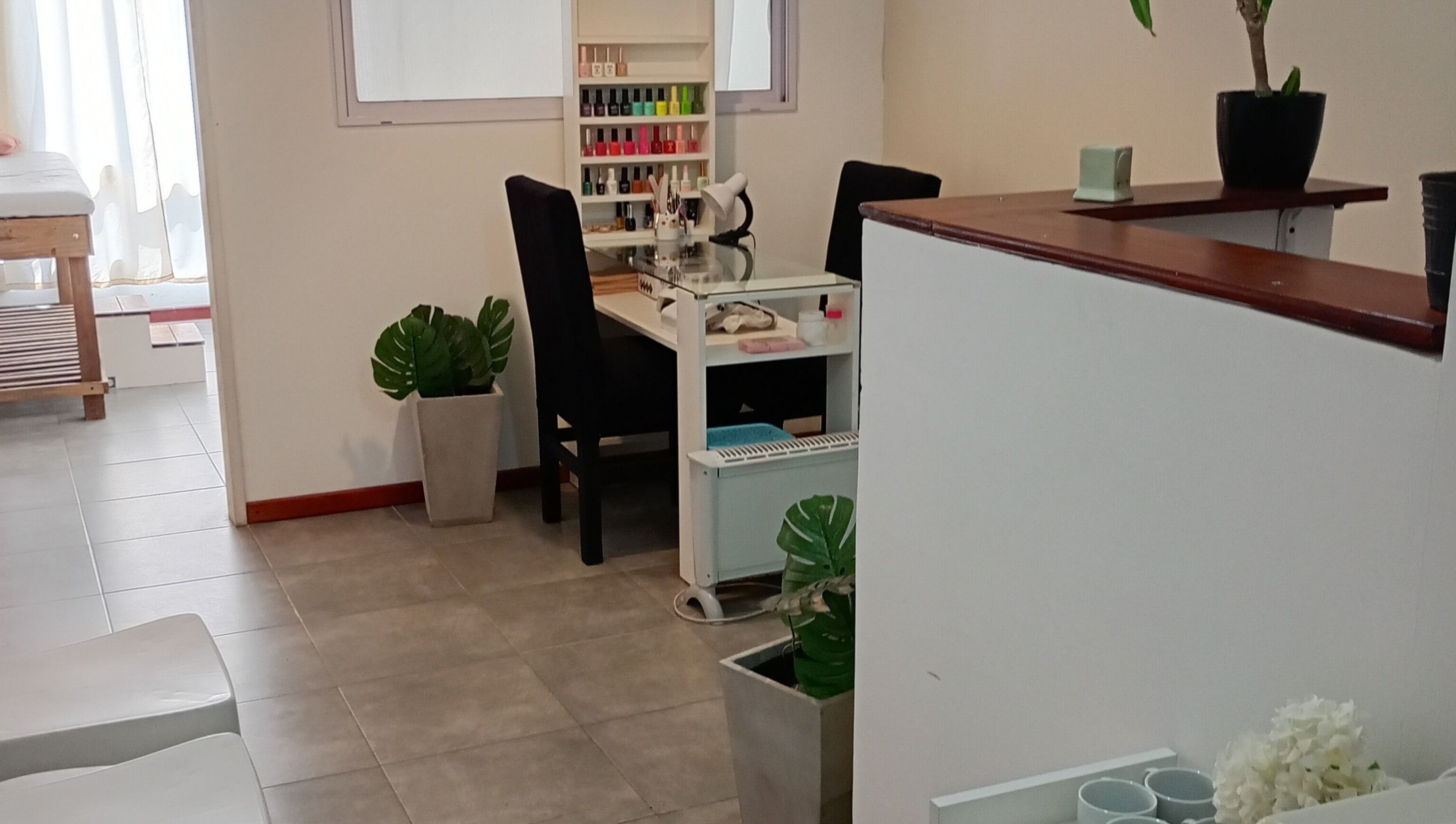 Salón acogedor en Piacere Micropigmentación, Córdoba, Córdoba, AR, con estación de manicura y plantas decorativas.