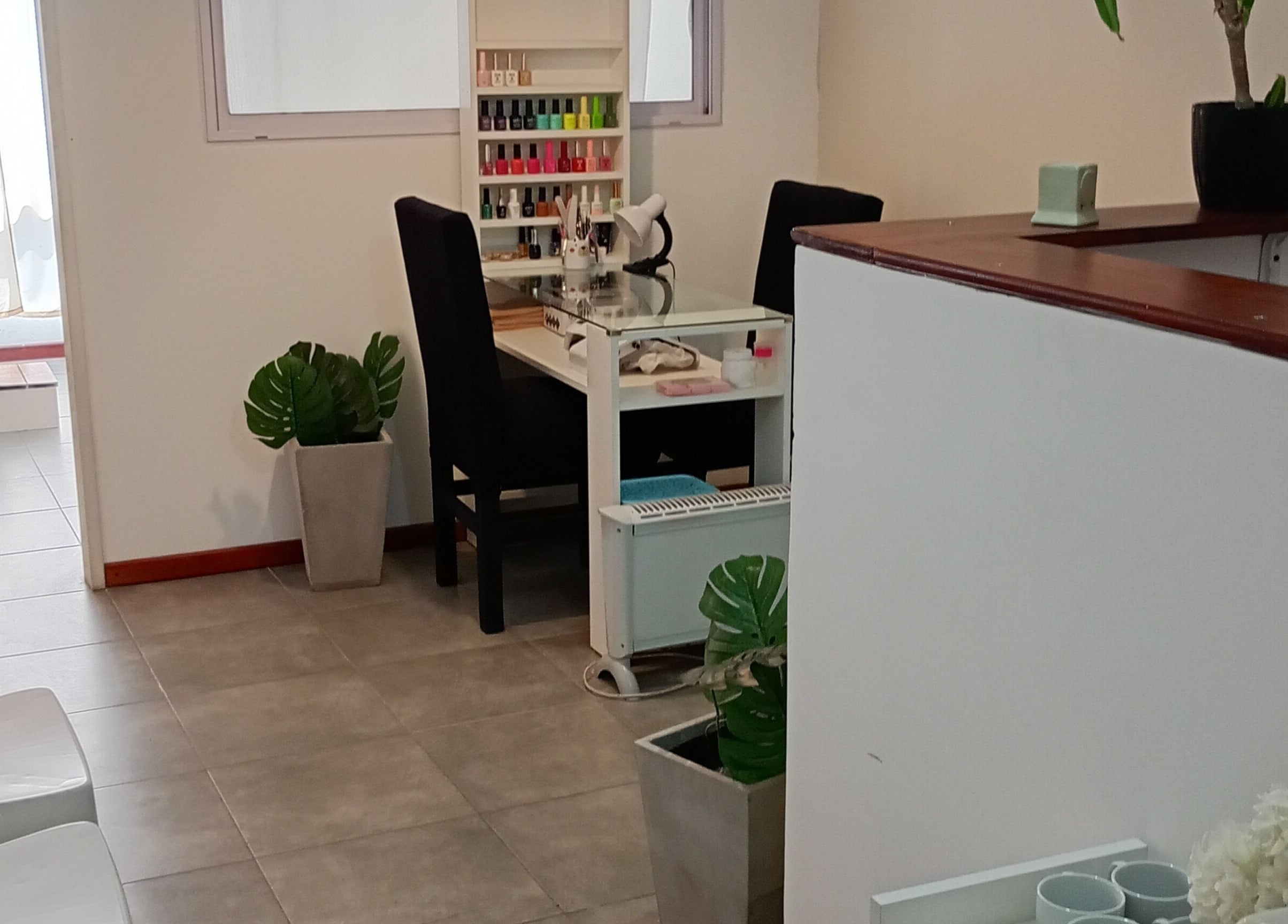 Salón acogedor en Piacere Micropigmentación, Córdoba, Córdoba, AR, con estación de manicura y plantas decorativas.